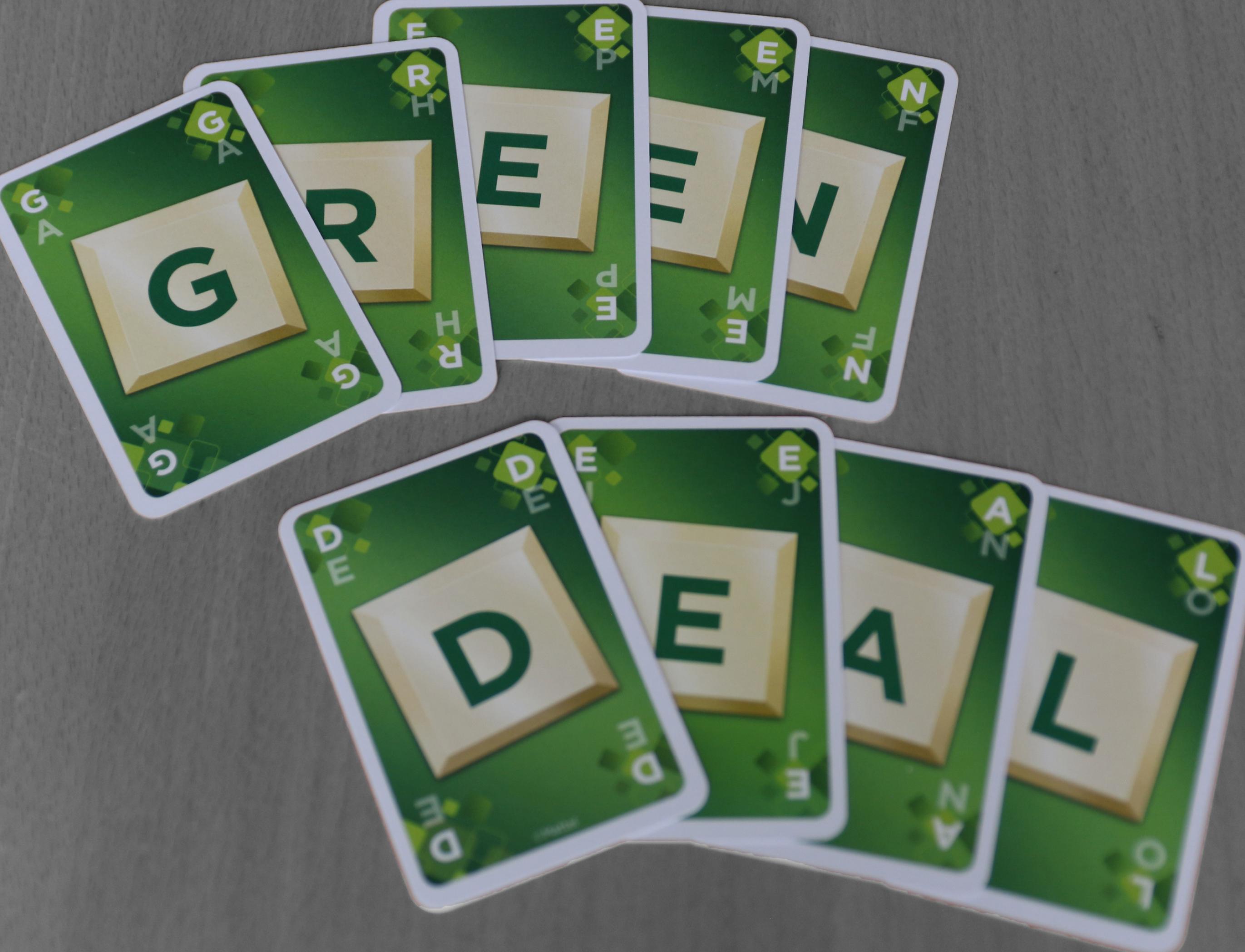 Auf einem Tisch liegen neun Karten mit Buchstaben, die zusammen „Green Deal“ buchstabieren. Während die Karten farbig und vor allem grün sind, ist die Tischoberfläche schwarz-weiß gehalten. – Der europäische Green Deal soll nach den Forderungen vieler Expert*innen aus Politik, Industrie und Zivilgesellschaft die graue Wirtschaft in eine grüne überführen.