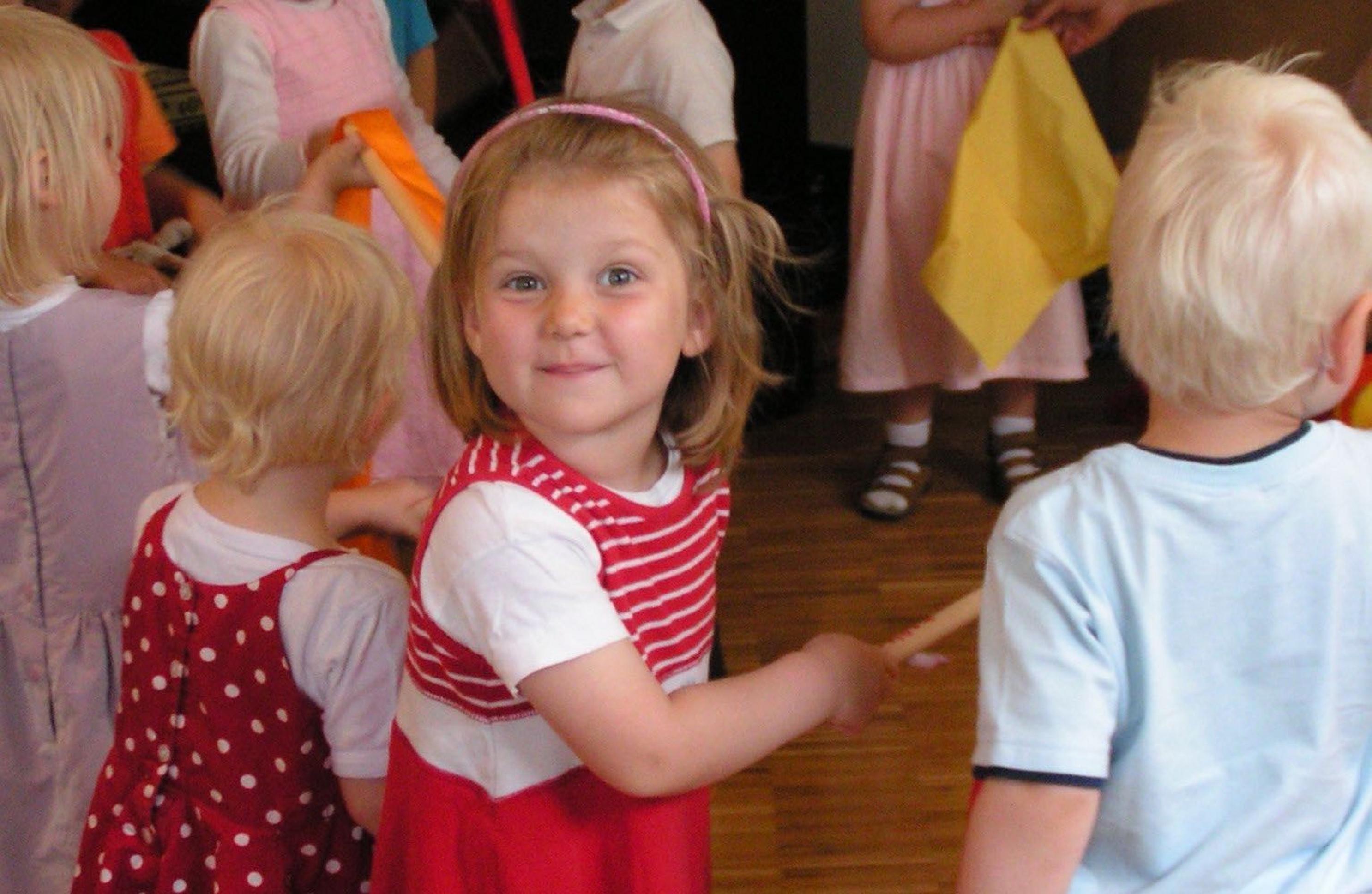 Eine Reihe von Kindern im Alter von ungefähr drei Jahren hält sich an den Händen. Alle stehen mit dem Rücken zur Kamera, nur ein Mädchen dreht sich um und grinst zum Fotografen. Schon im Kindergartenalter löst jedes Kind viele Tonnen von Emissionen aus – und alles auf Rechnung von Mama und Papa, sagt die Studie.