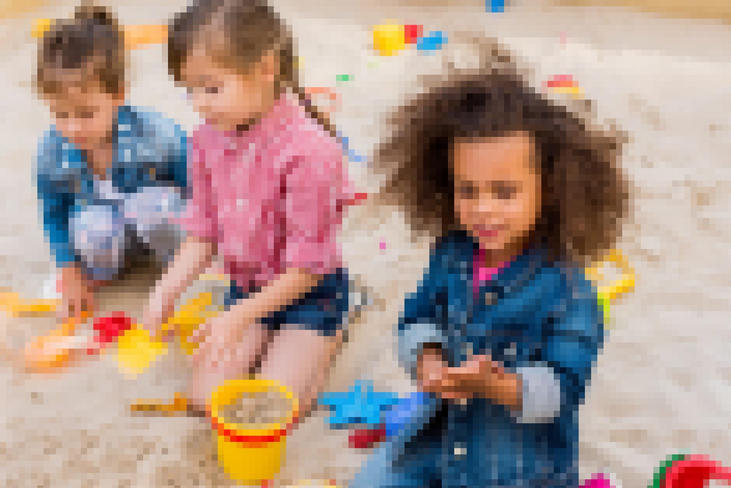 Drei Mädchen spielen im Sand