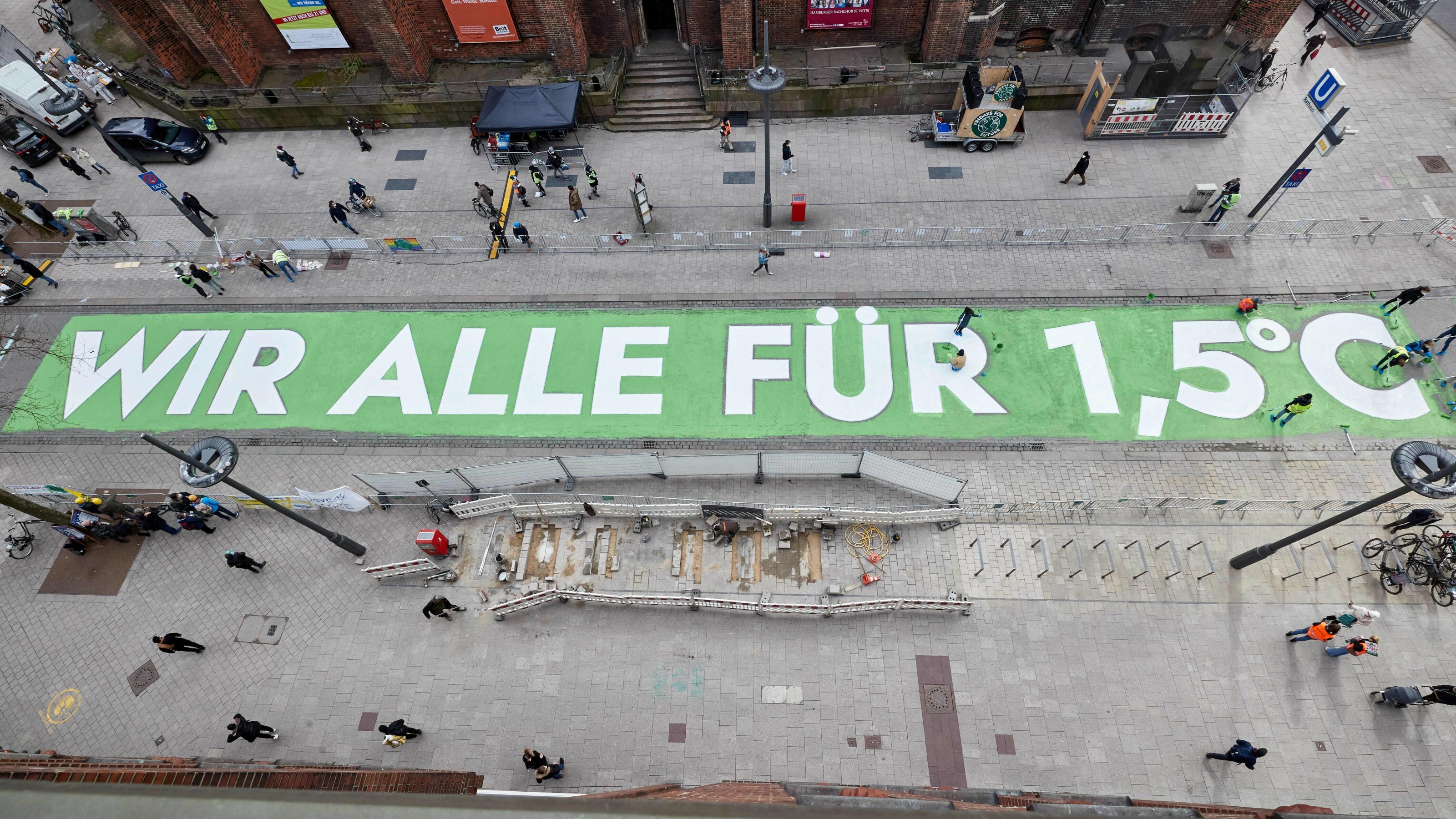 Aktivisten von Fridays for Future malen den Schriftzug „Wir alle für 1,5 Grad“ auf die Mönckebergstraße in Hamburg.