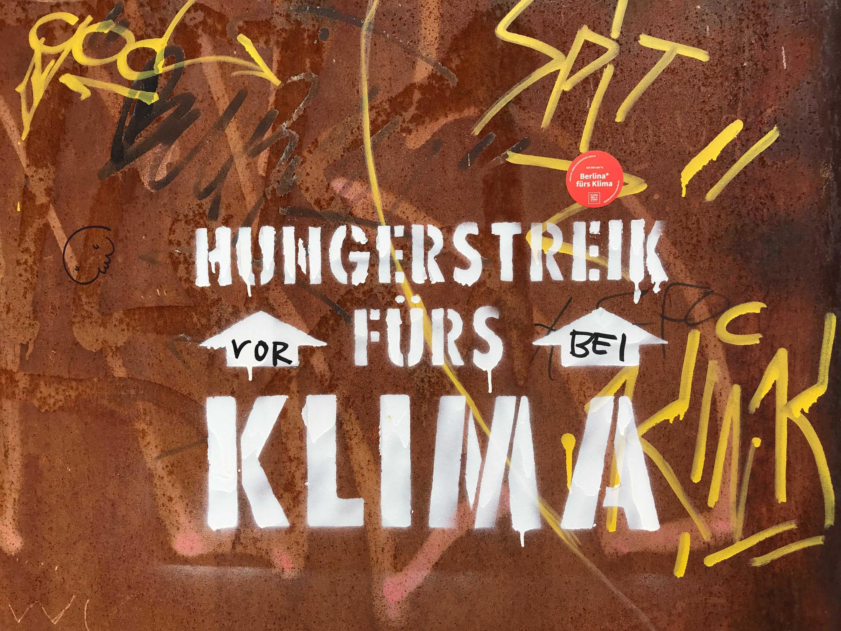 Ein handgemaltes Schild weist auf das Klimacamp im Berliner Spreeebogen hin. Dort sind Klimaaktivisten im Hungerstreik.