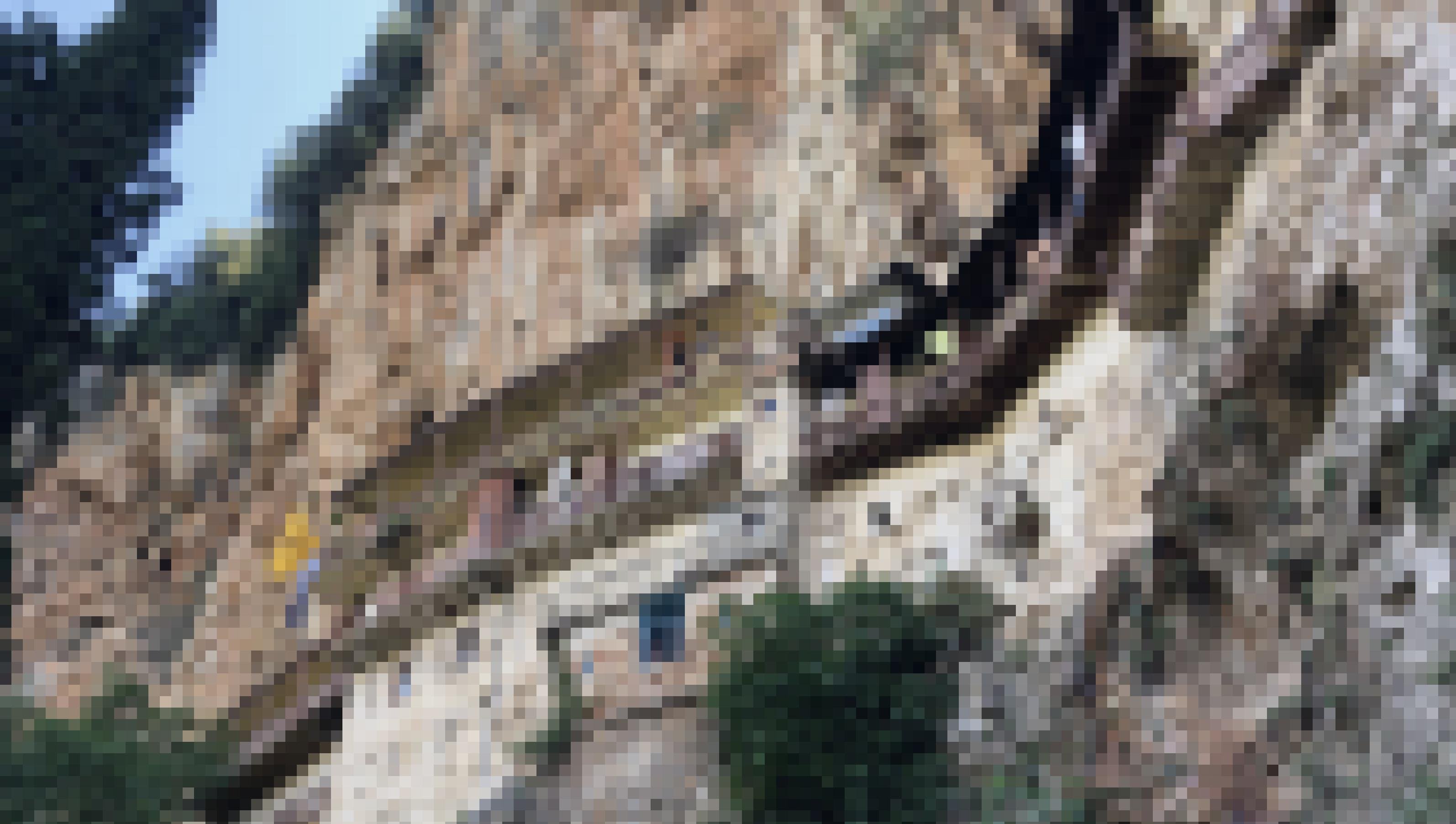 Eine Reihe von Häusern klebt spektakulär hoch oben in einer steilen Felswand.