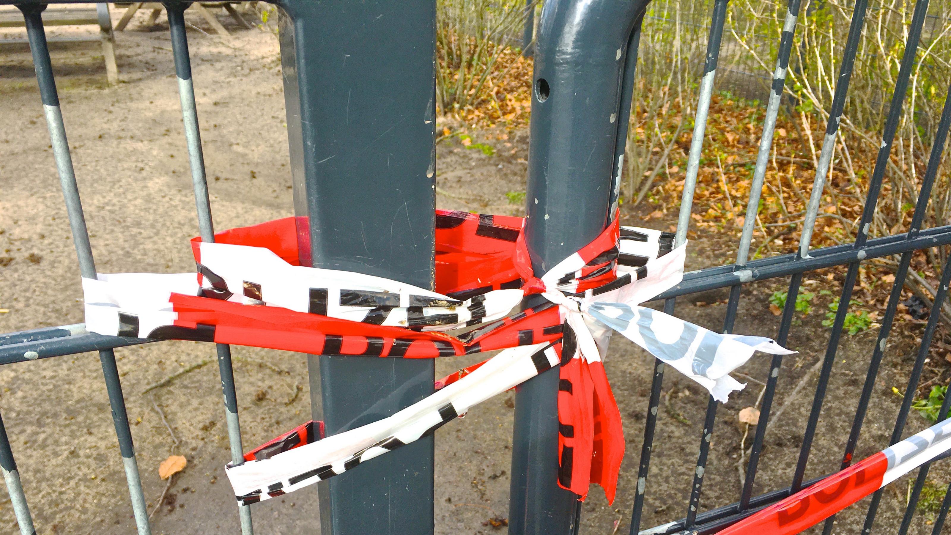 Die Teile eines Metalltors sind mehrfach umwickelt und dann verknotet, um den Durchgang zu sperren. Gesehen in einem Hamburger Park.