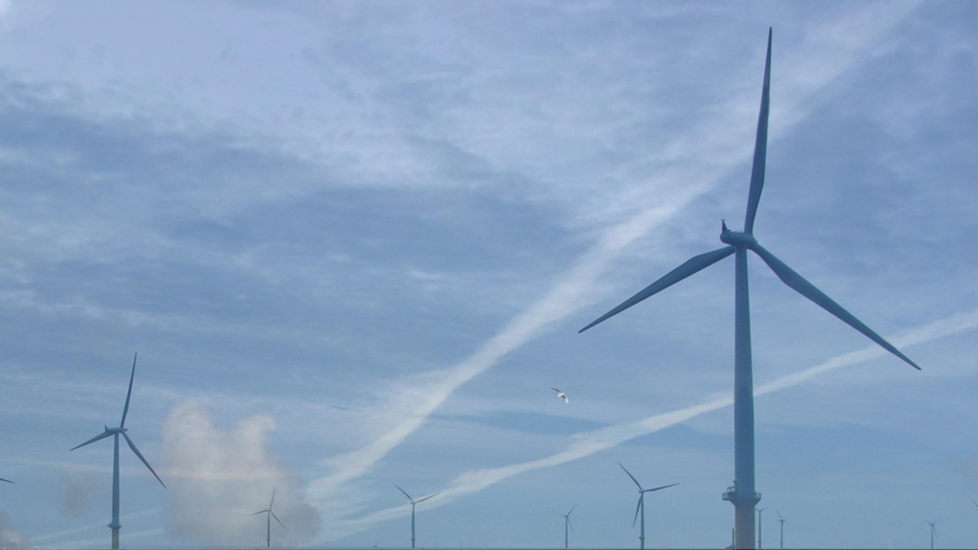 Ein Blick in den blauen Himmel, dort sieht man Kondensstreifen hinter Windrädern. Fotos und Montage: Christopher Schrader