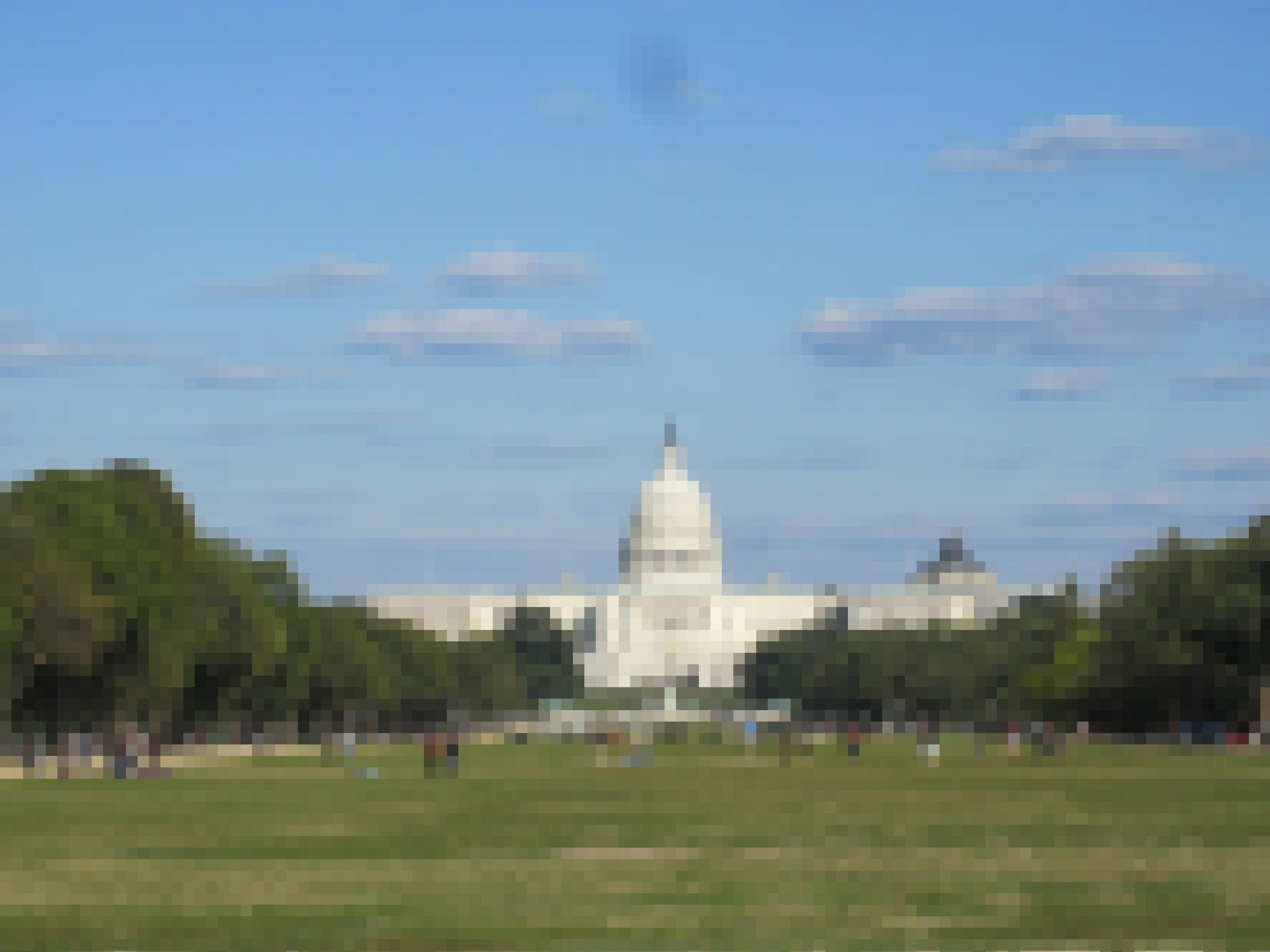 Das Kapitol in Washington, D.C. Im Vordergrund halten sich Menschen auf dem Rasen auf.