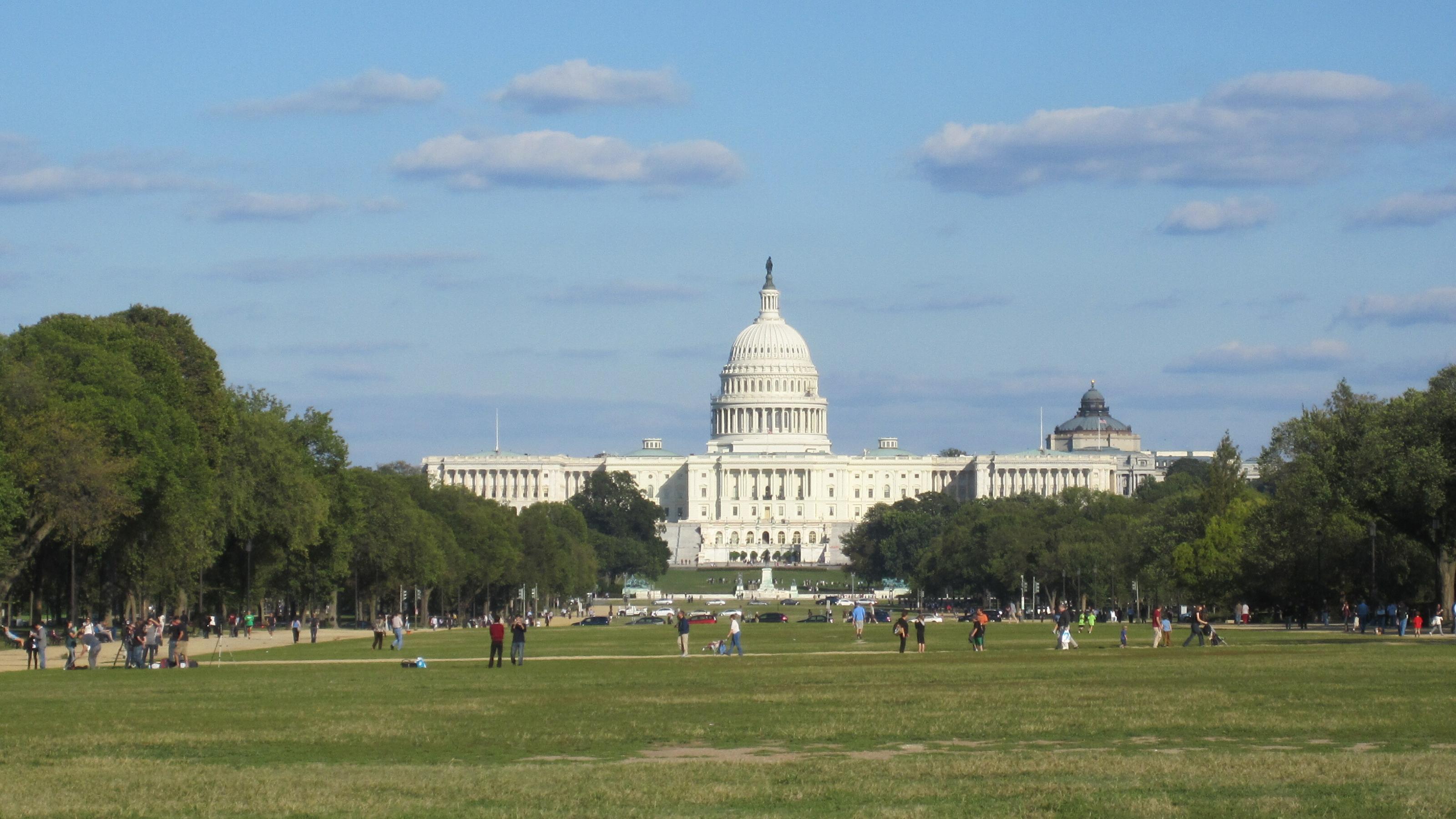 Das Kapitol in Washington, D.C. Im Vordergrund halten sich Menschen auf dem Rasen auf.