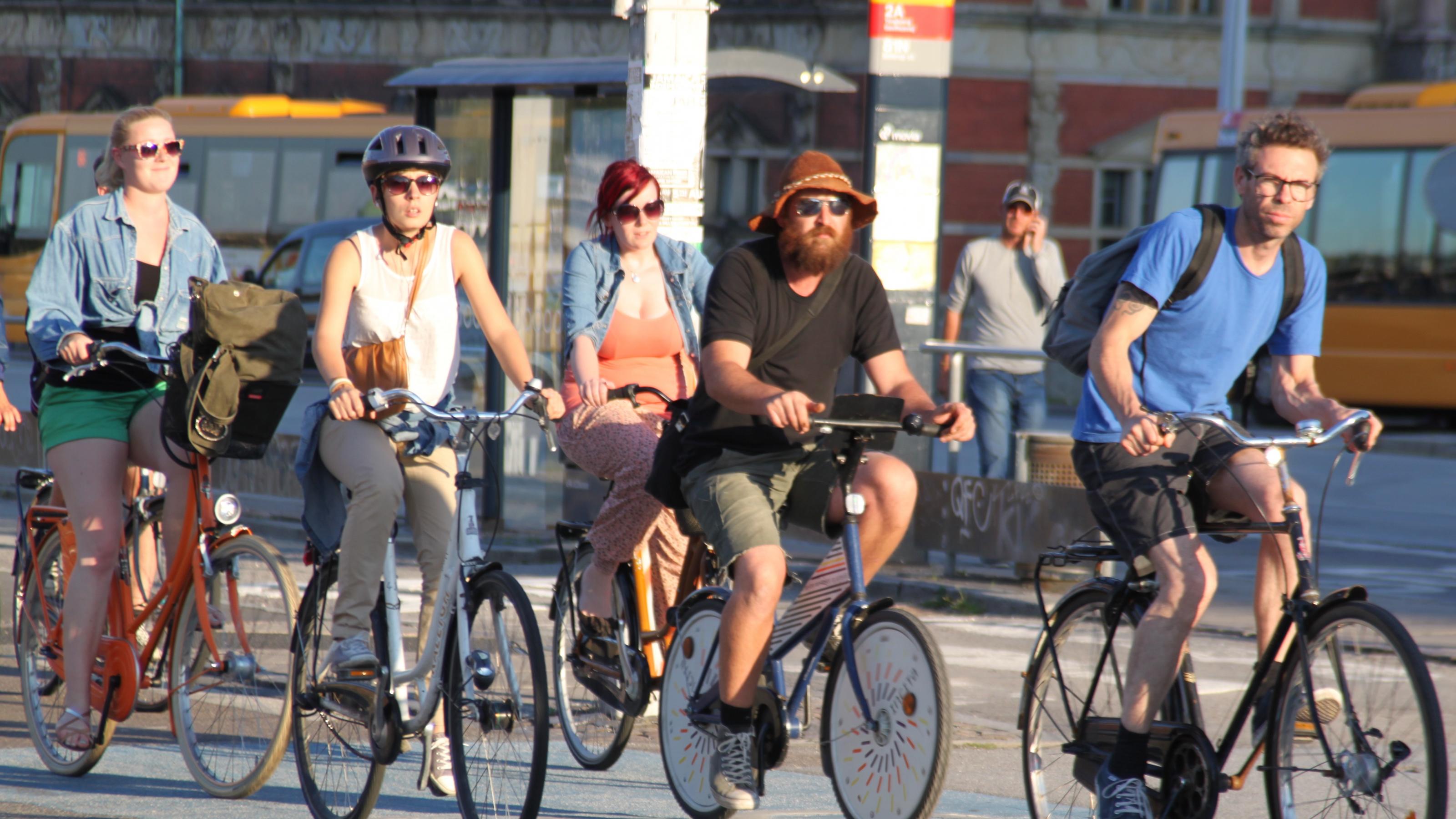 Fünf Radfahrer überqueren auf einem breiten blau gefärbten Radweg entspannt eine Kreuzung.