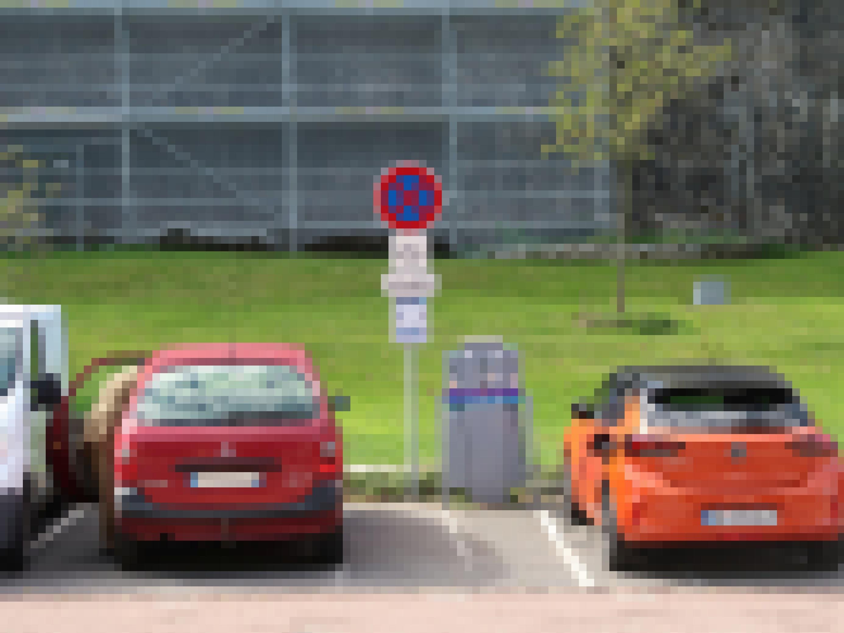 Zwei Auto stehen auf einem Parkplatz, eines davon ist an einer Ladestation angeschlossen.