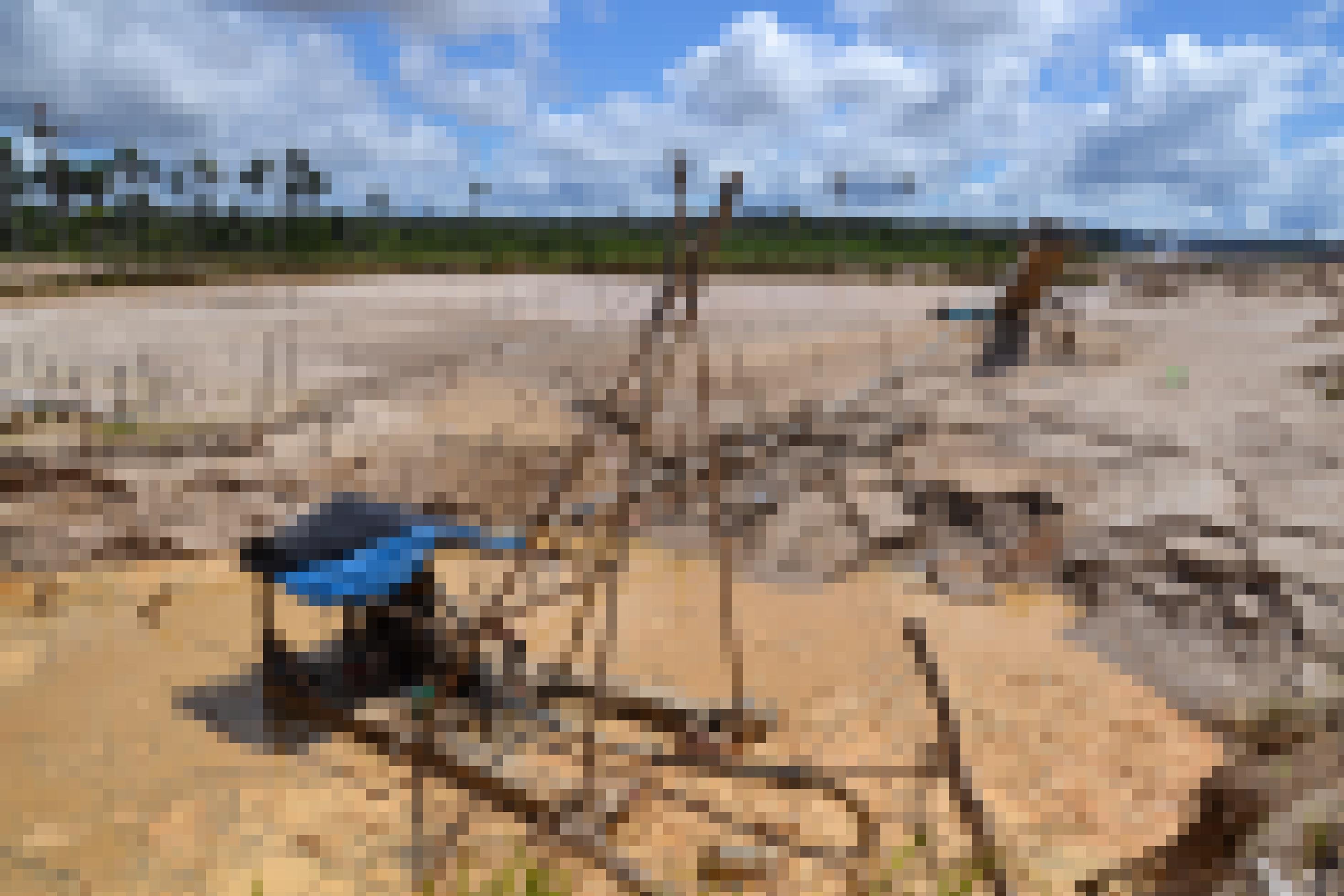 Eine Holzhütte mit blauer Plastikplane umgeben von Sand und einer schmutzigen Wasserpfütze.