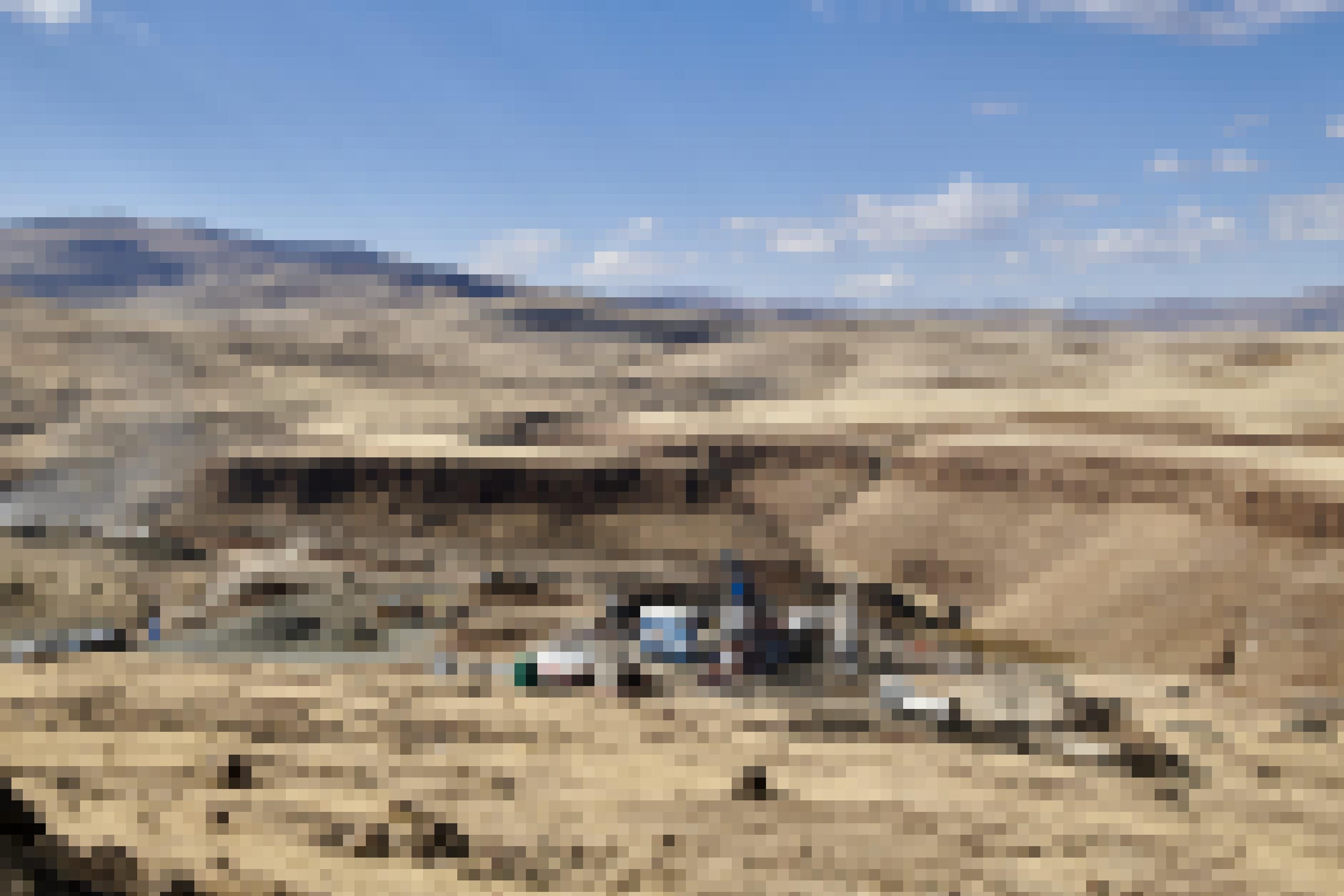 Im Tal der fahlgelben Graslandschaft sind Bauarbeiten und LKW zu sehen