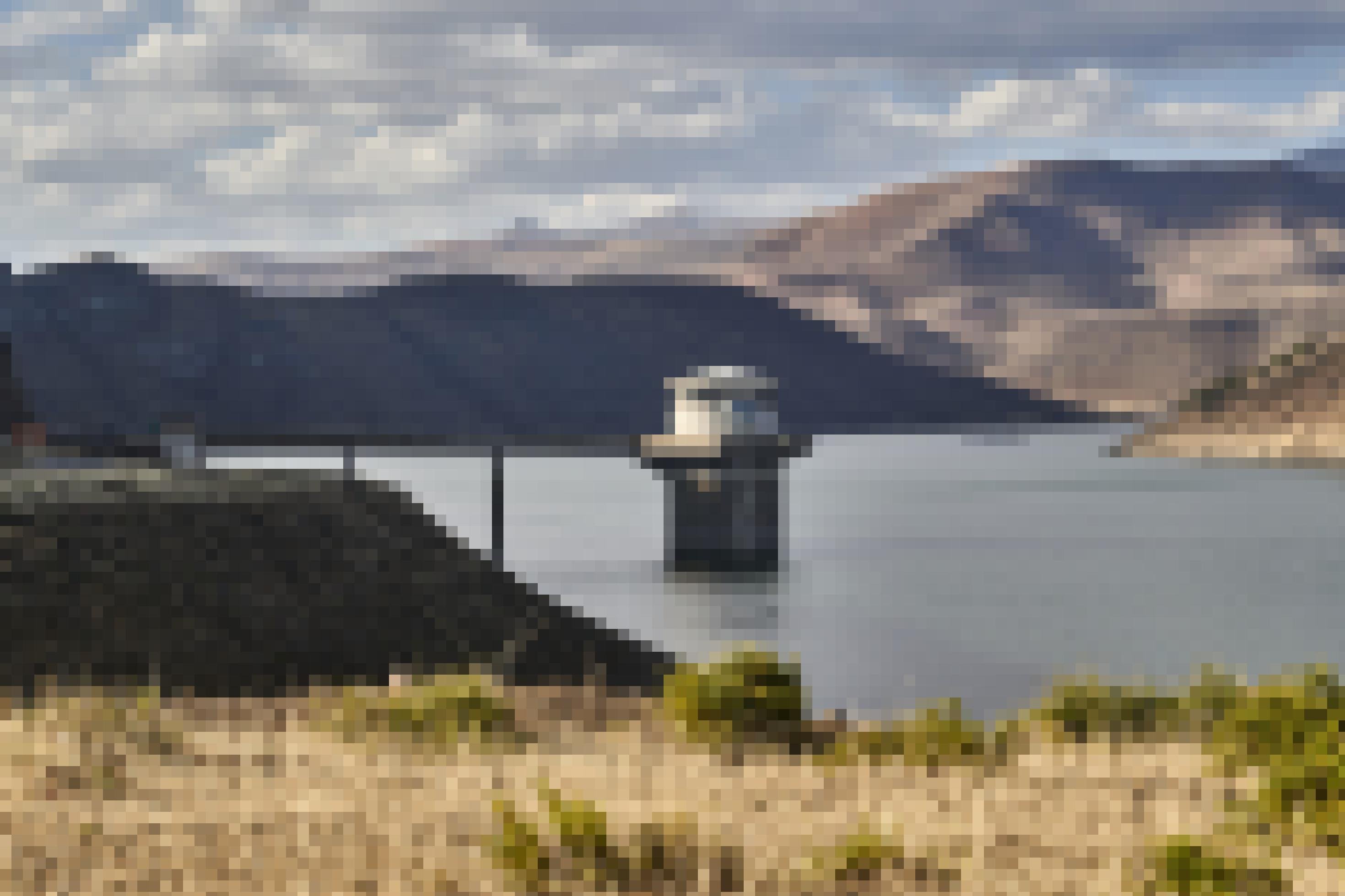 Auf dem Stausee  vor der Bergkulisse ragt ein Betonturm – die Pumpstation