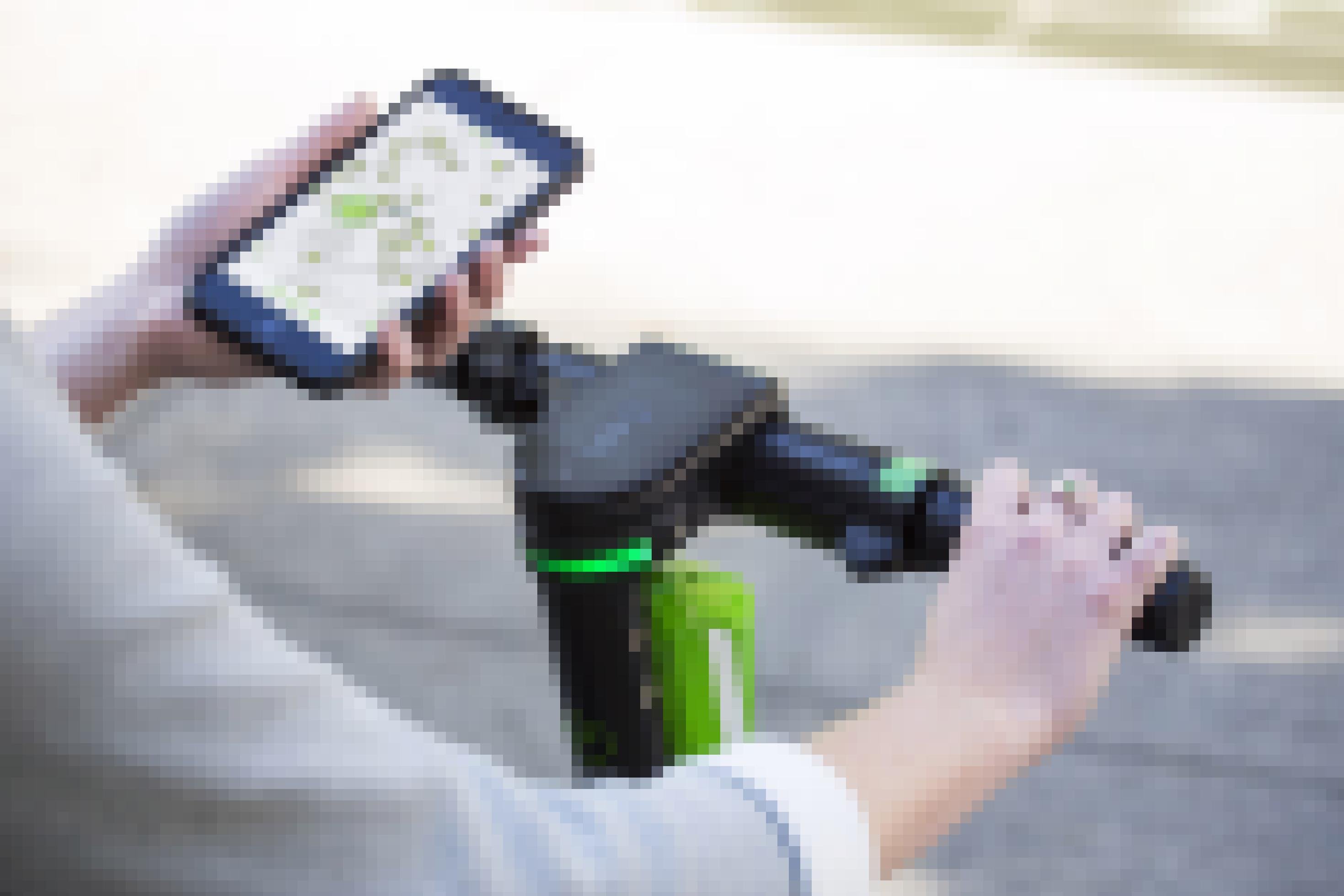 Blick auf den Lenker des E-Scooters mit Display. Die rechte Hand einer Frau hält den Griff des Lenkers, während sie in der linken Hand ein Smartphone mit einer geöffneten Navi-App hält.