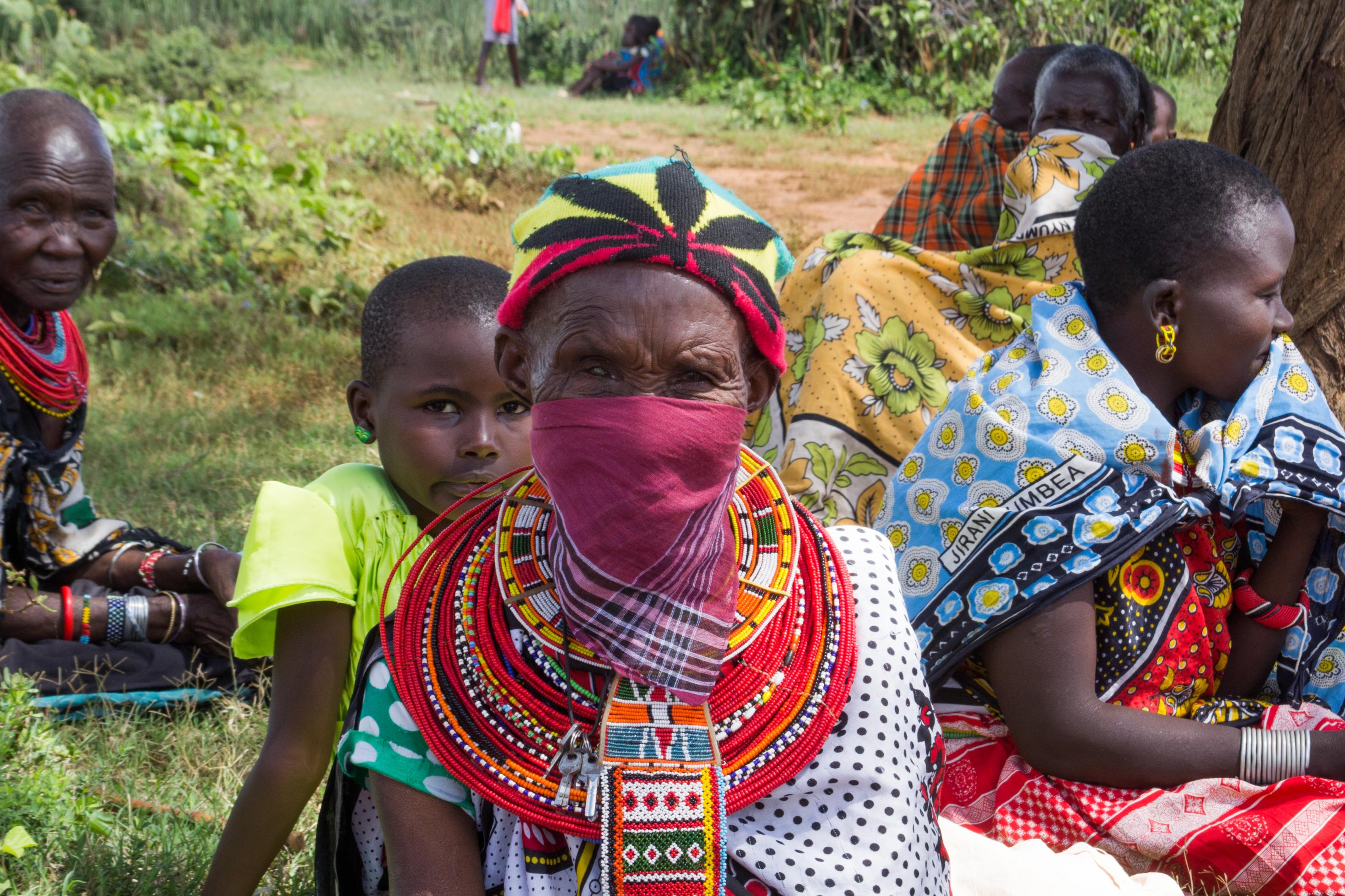 Einige Maasai-Frauen tragen mit Gesichtsmasken. Im Bild ist eine, die zu einer violetten Gesichtsmaske ein Kopftuch mit einer Cannabis-Pflanze trägt. Bisher gab es in der Region noch keine bekannten Infektionsfälle.