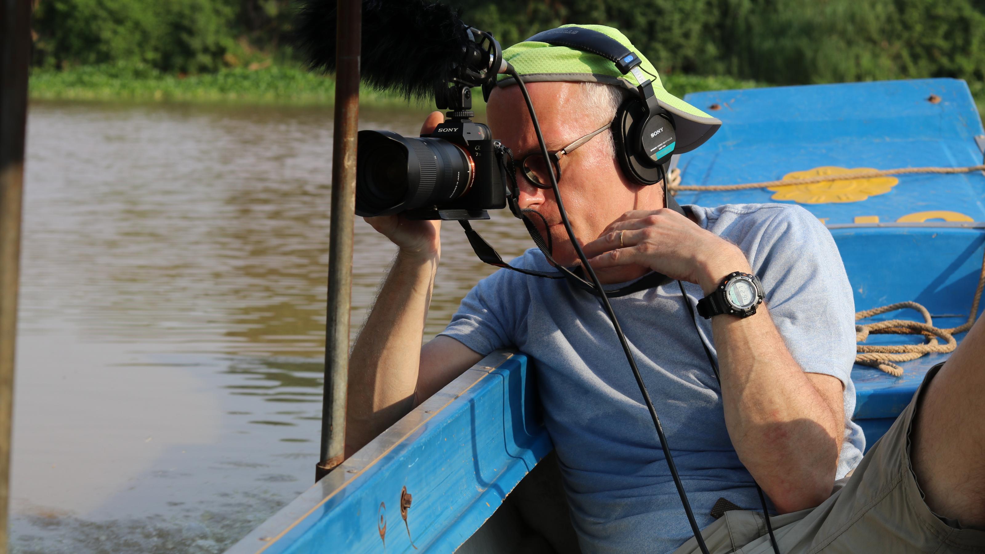 ein Mann mit Kopfhörern und einer Kamera in einem Boot [AI]