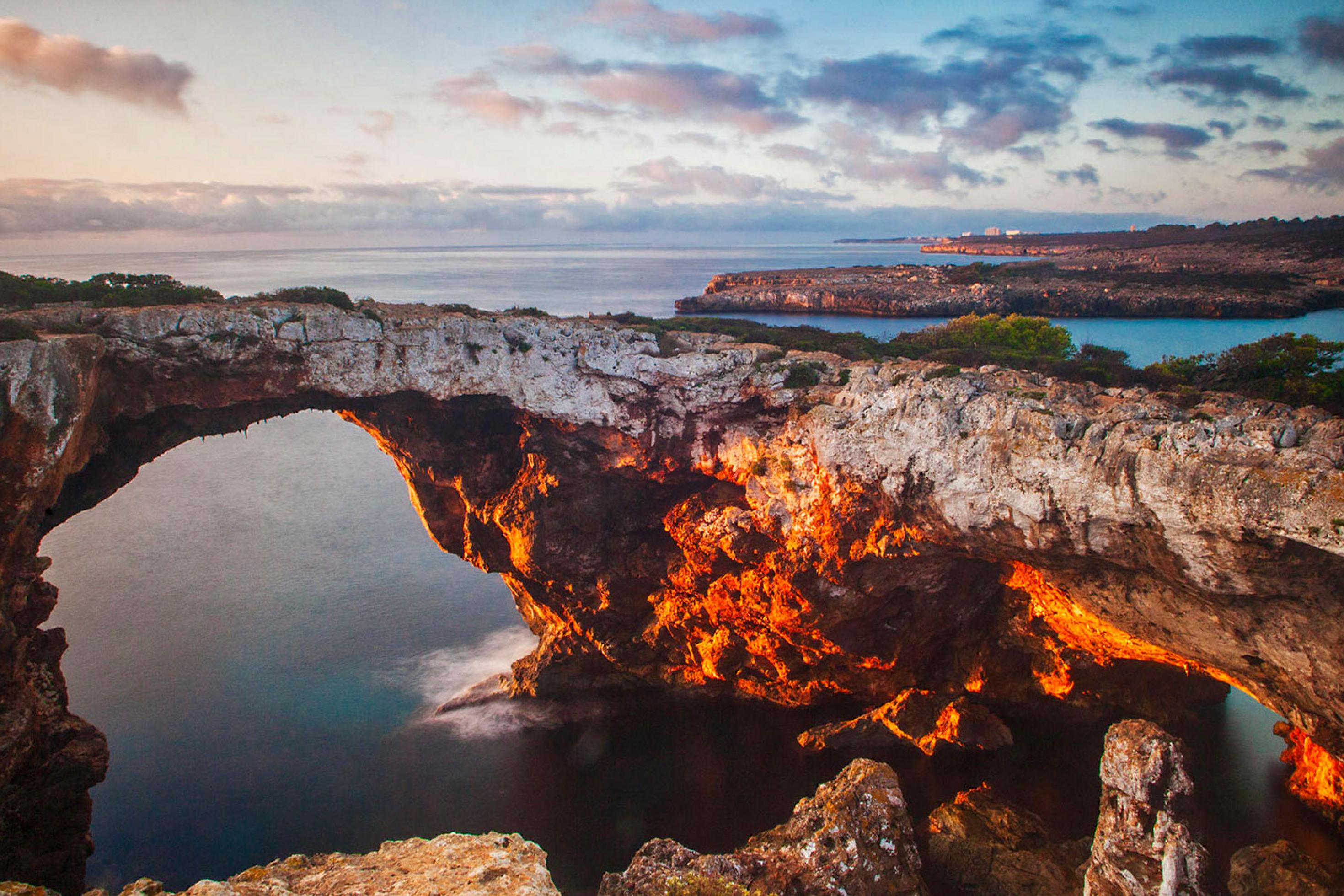Morgendlicher Blick mit Sonnenstrahlen auf die Felsen der Bucht Cala Varques auf Mallorca