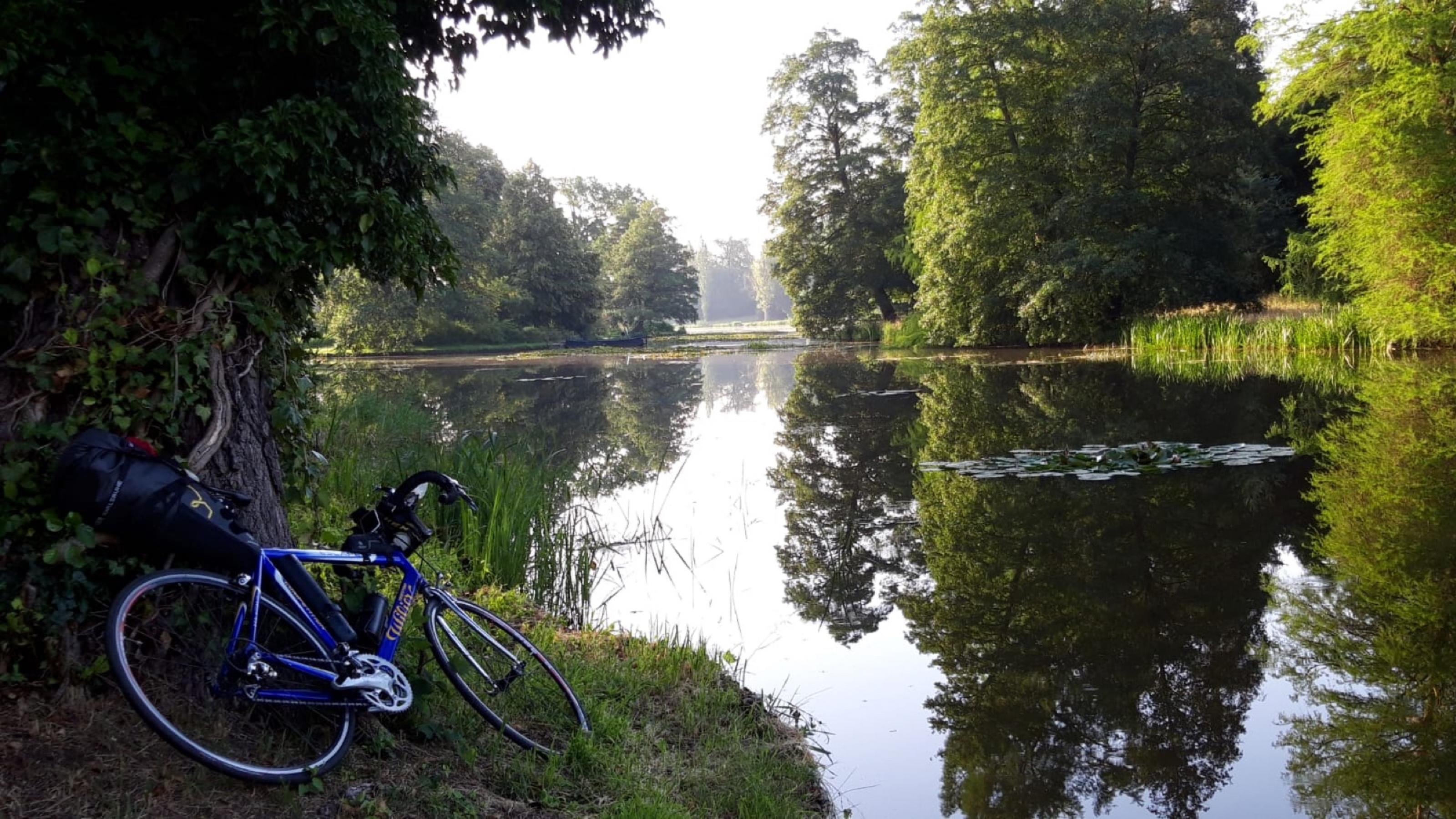 Ein blaues Rad liegt am Ufer eines Sees.