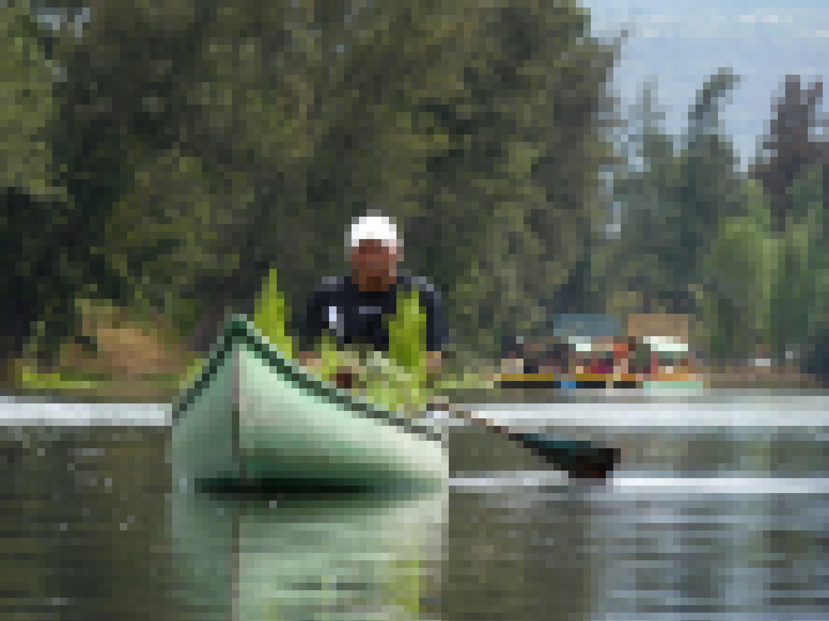 Ein älterer Mann in einem Holzkanu, das mit Gemüse beladen ist. Er ist unterwegs mit seiner Ernte im Lagunensystem von Xochimiico im Süden von Mexiko-Stadt.