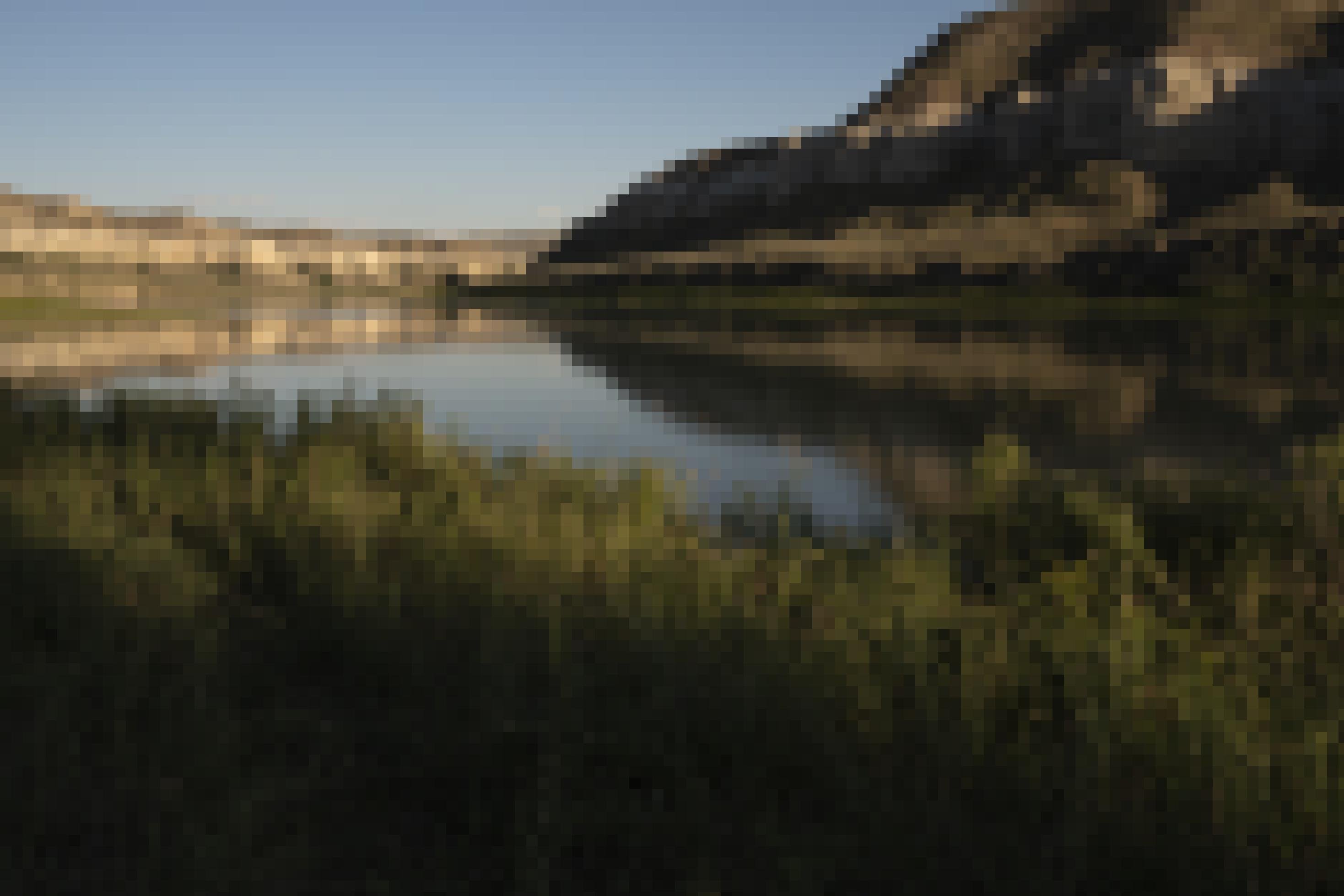 Der Missouri River biegt um eine Rechtskurve und leuchtet tiefblau gegen das goldene Abendlicht der umgebenden Felsformationen.