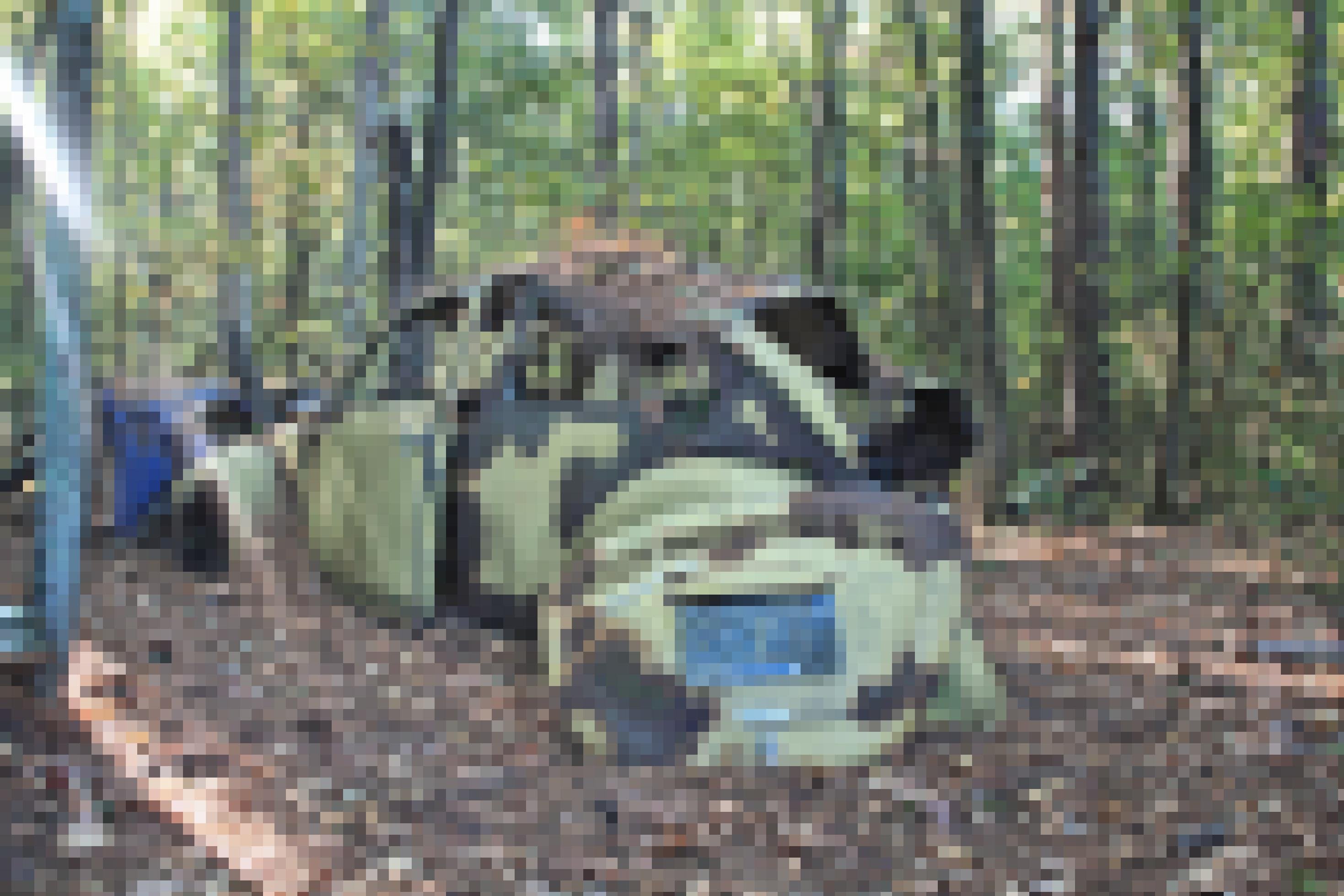 Ein zerfallener VW Käfer in einem Wald.
