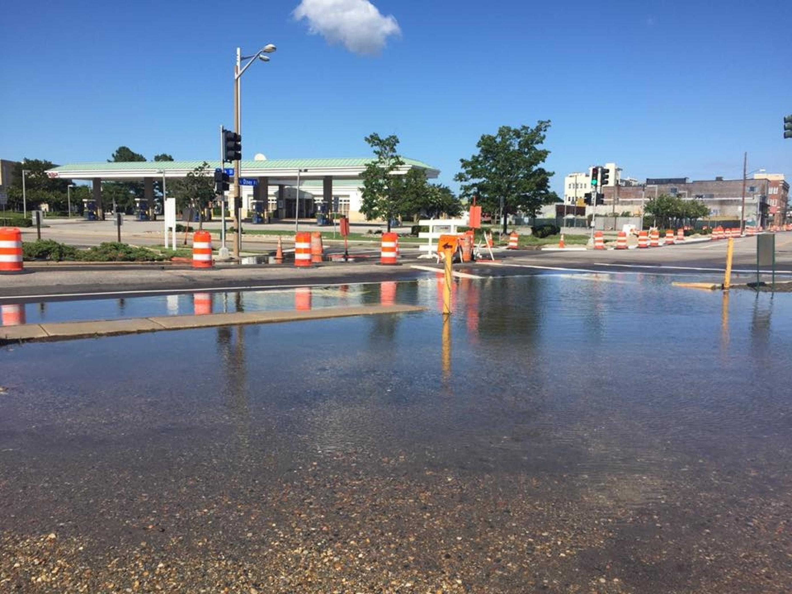 Eine spiegelnde Wasserfläche unter blauem Himmel, umgeben von Orang-weißen Signaltonnen und im Hintergrund von Häusern. –
Der Parkplatz an der Olney Street steht mal wieder unter Wasser. Das passiert so oft, dass die Anwohner im Stadtteil Ghent von Norfolk/Virginia schon von Lake Olney sprechen.