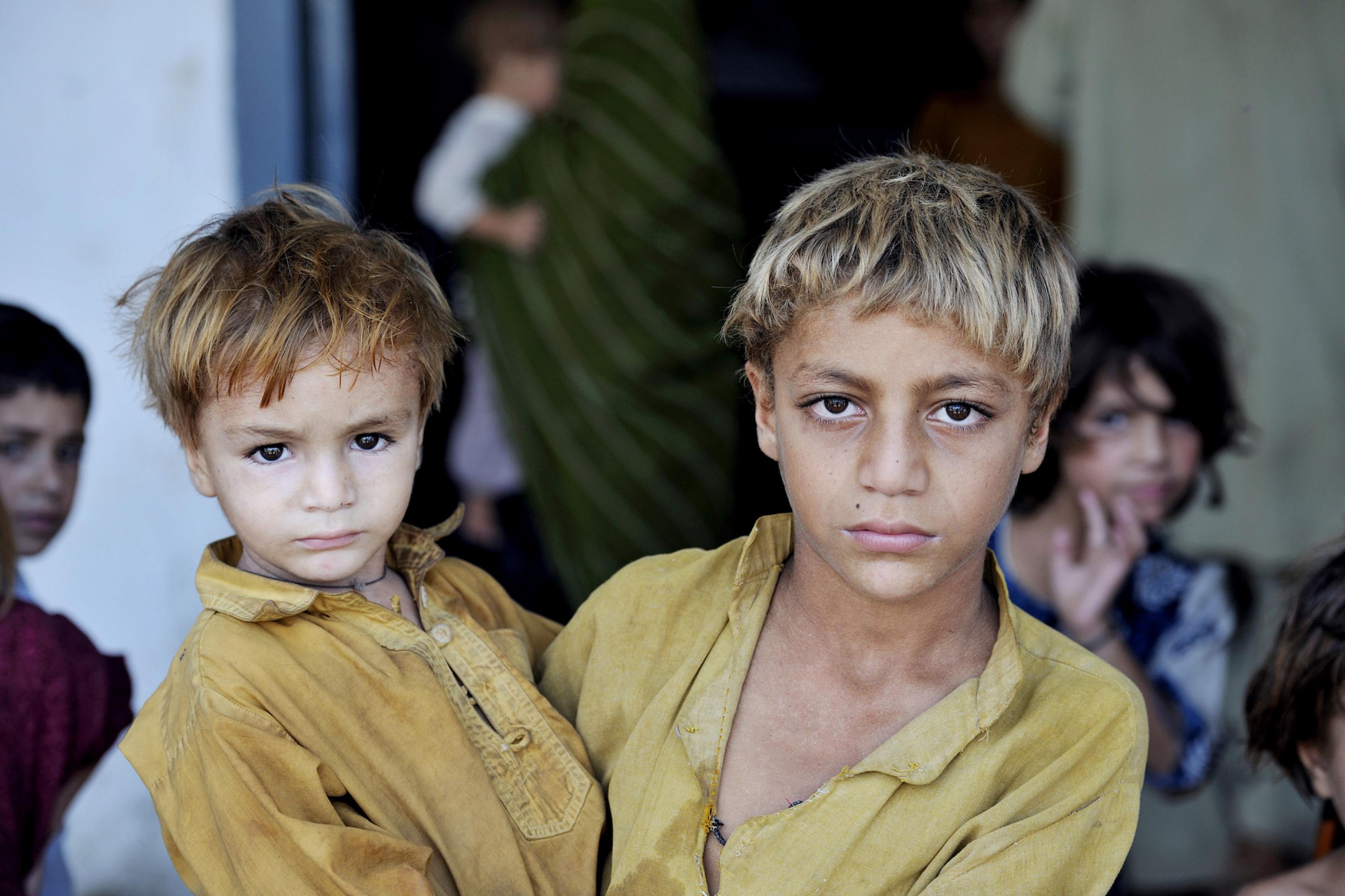 Ein älterer Junger hält seinen jüngeren Bruder auf dem Arm, beide schauen ernst in die Kamera. Dieses Bruderpaar fand damals – wie Tausende andere – Zuflucht in einer Schule des Charsadra-Distrikts in der nordwestlichen Grenzprovinz Khyber Pakhtunkhwa.