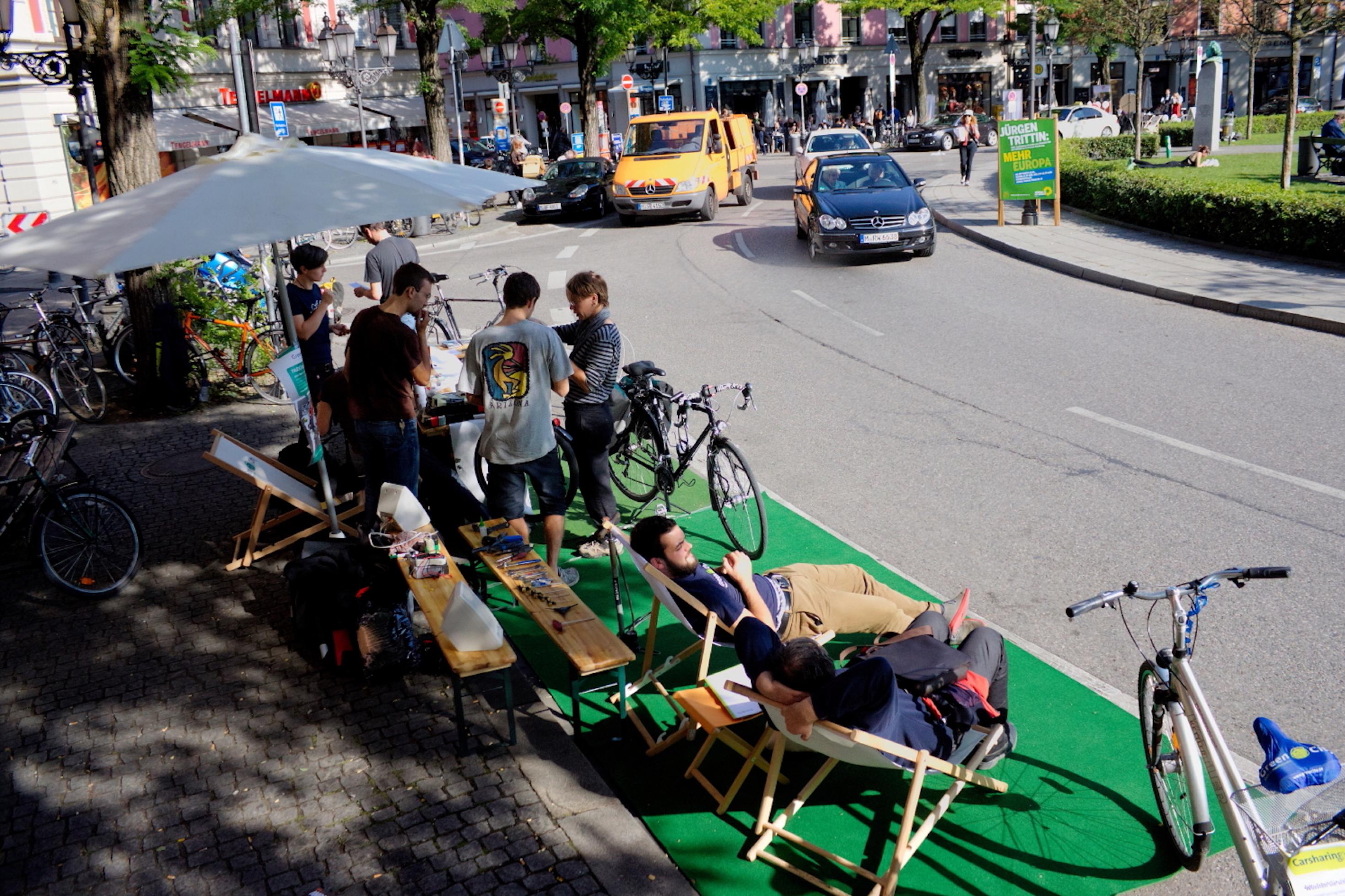 Aktivisten haben einer beiden Seiten der zweispurigen Straßen Rasen ausgerollt und liegen entspannt unter Sonnenschirmen in ihren  Liegestühlen