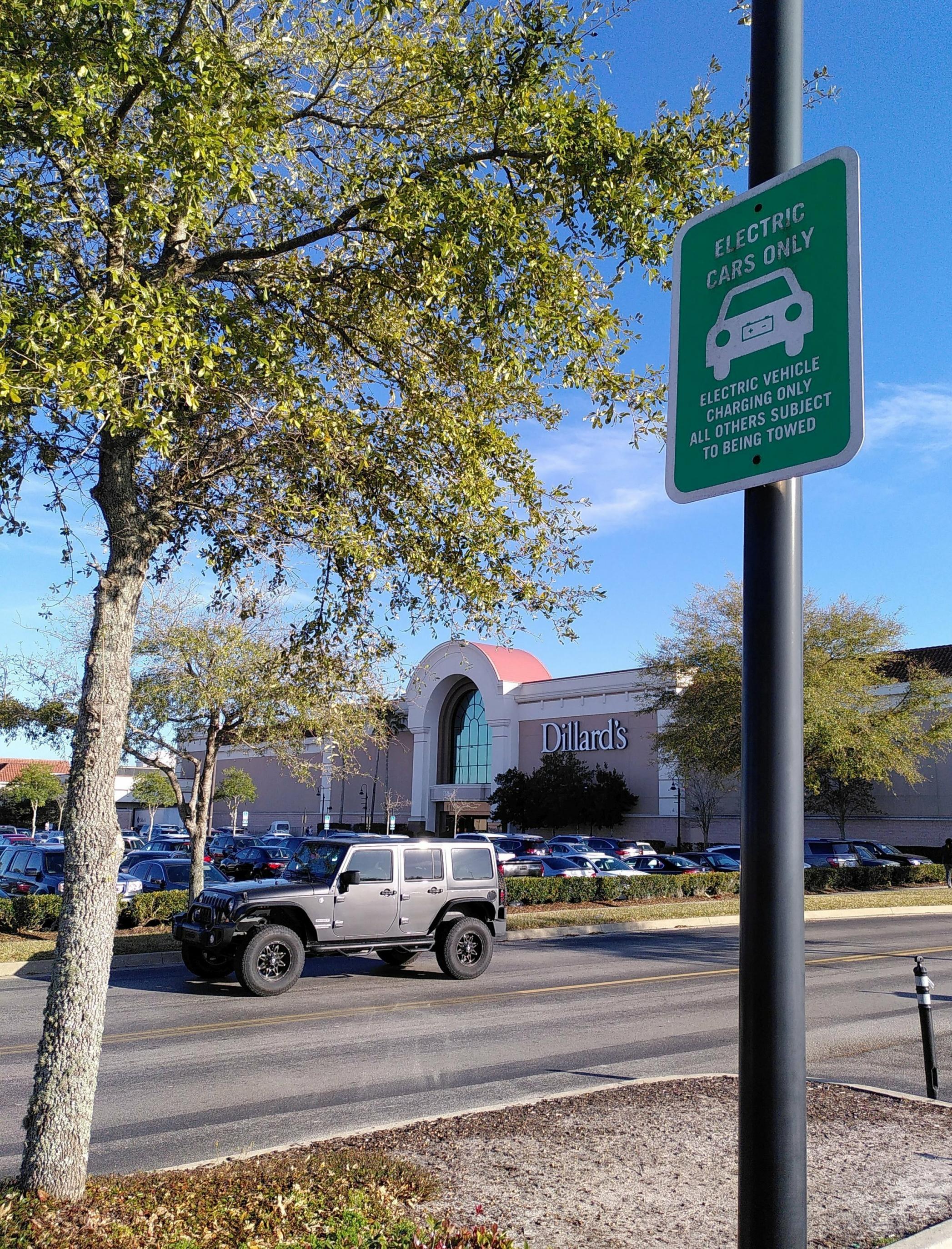 Ein Parkplatz. Im Vordergrund ist ein Schild zu sehen, auf dem steht: „Electric cars only“.