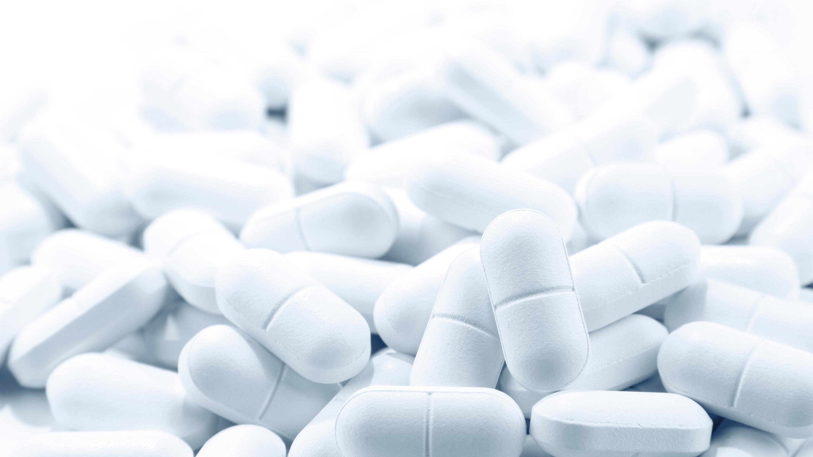 Das Bild zeigt eine große Zahl von weißen Tabletten auf einem Haufen. Das soll symbolisieren, dass es bisher keinen Wirkstoff gibt, aber mit Hochdruck nach ihm gesucht wird.