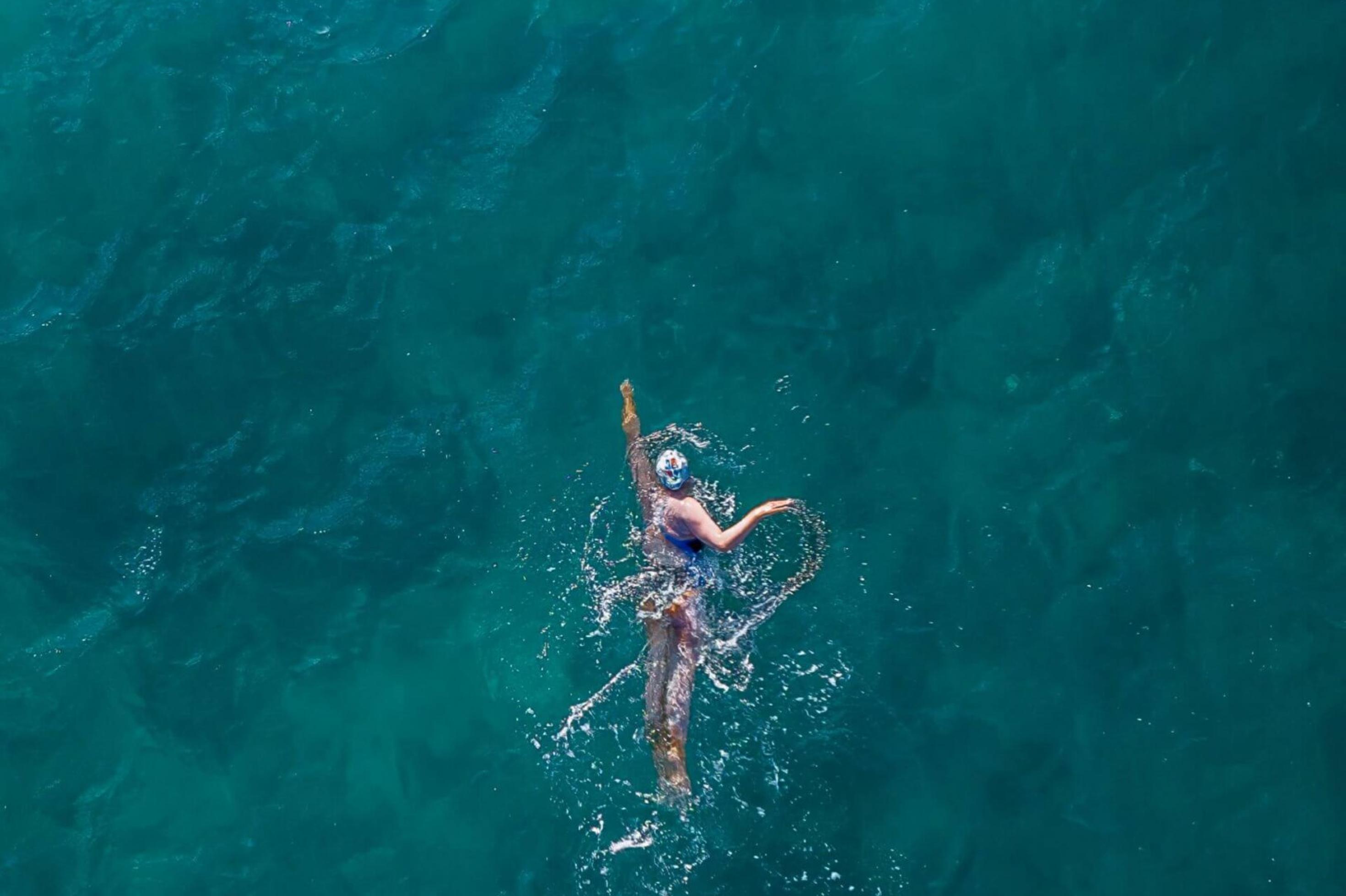 Frau schwimmt in türkisem Meer. Aufnahme von oben