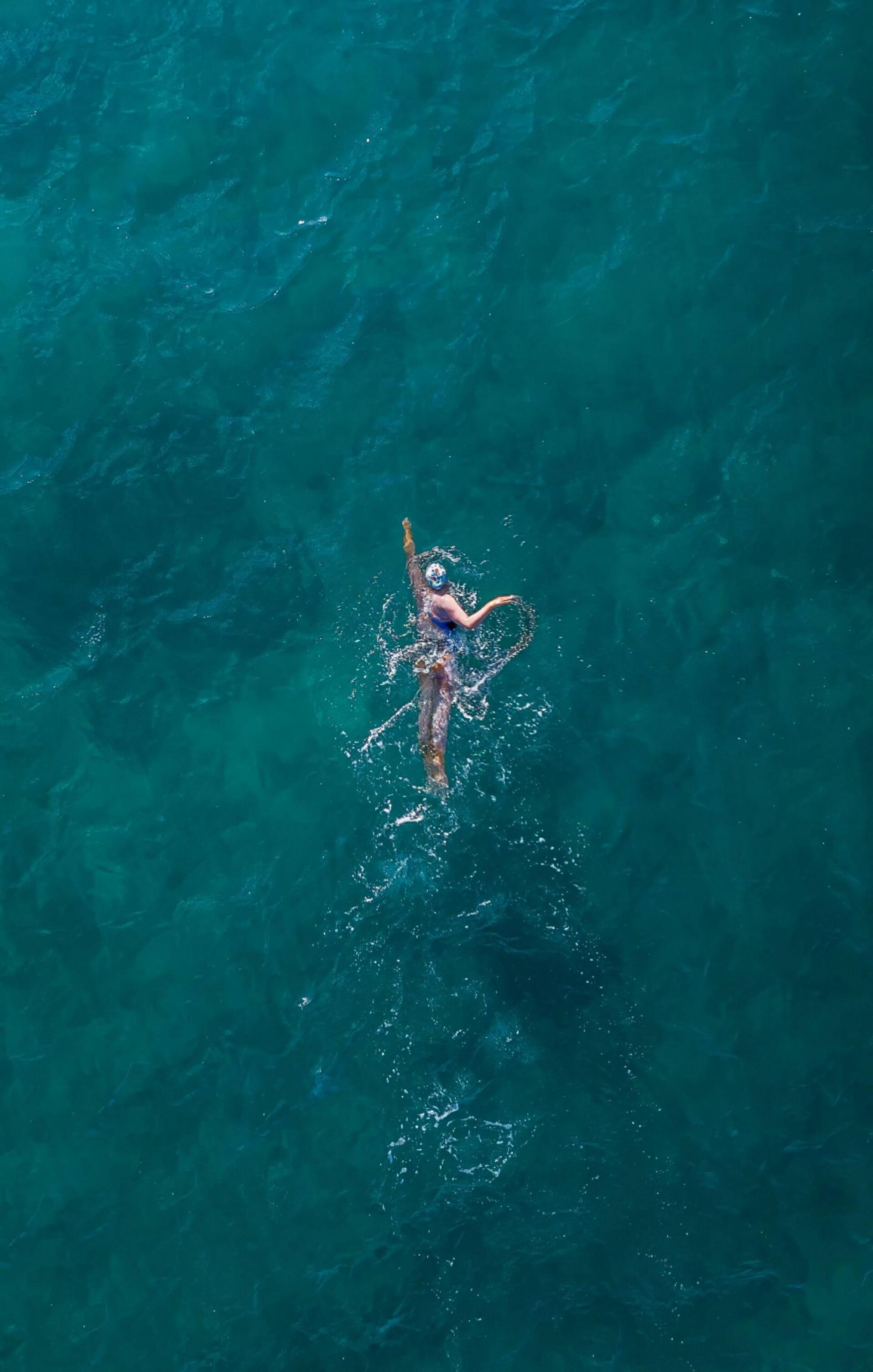 Frau schwimmt in türkisem Meer. Aufnahme von oben