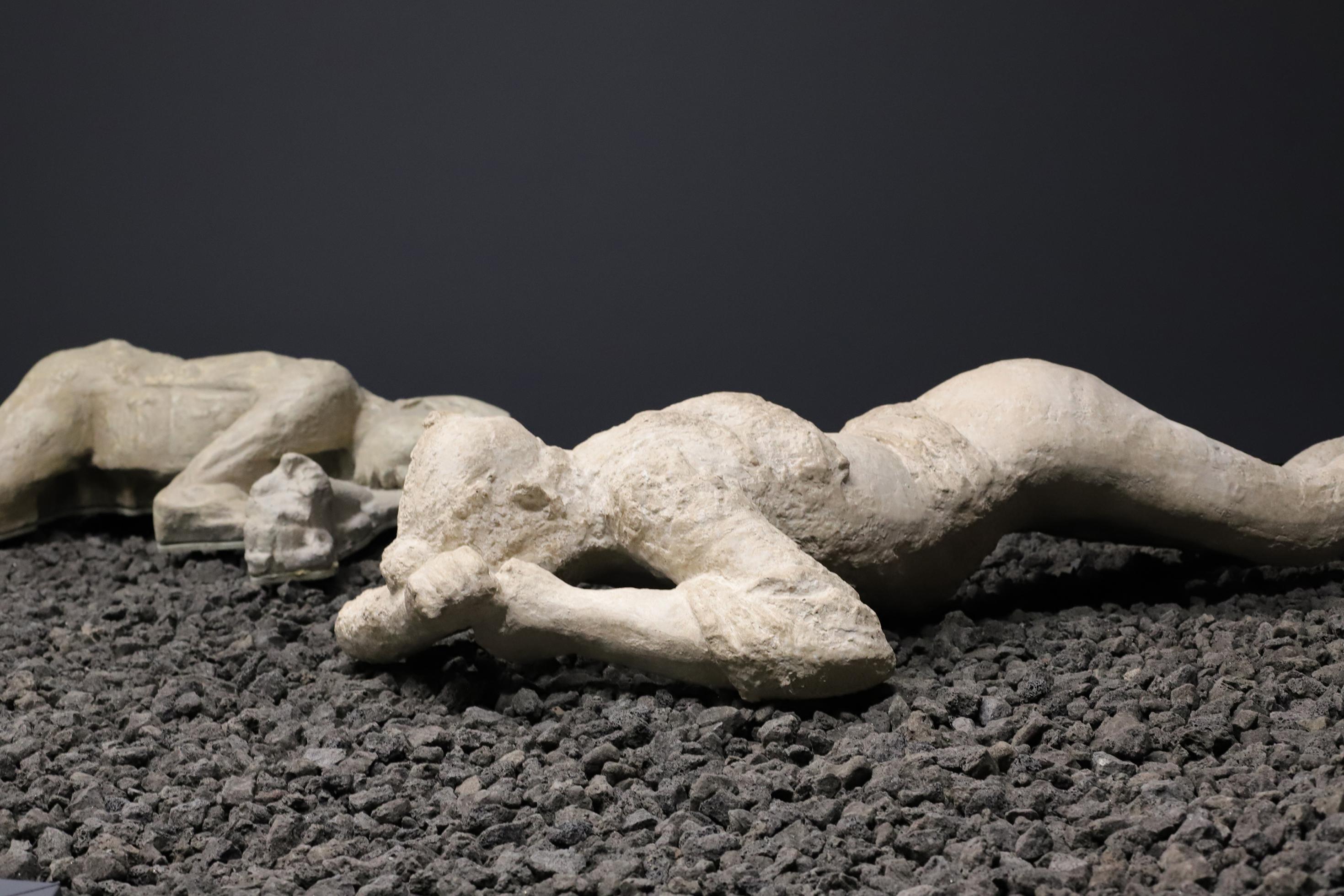 Das Bild zeigt den weißen Gipsabdruck eines auf dem Boden liegenden Menschen, der beim Ausbruch des Vesuv im Jahr 79 n. Chr. ums Leben gekommen ist.