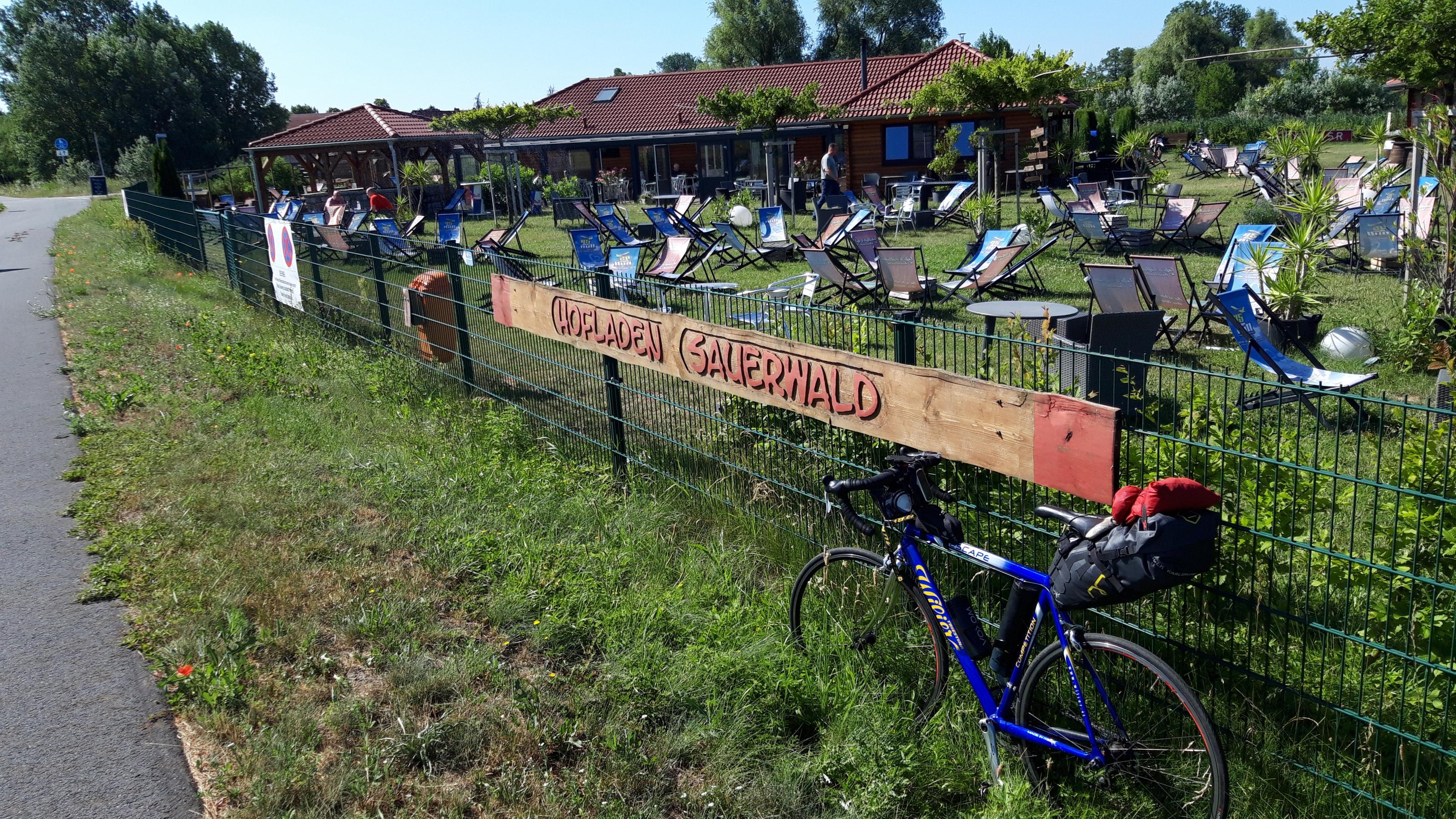 Das Rad des RadelndenReporters lehnt am Zaun, hinter dem sich Liegestühle auf einer Wiese verteilen.