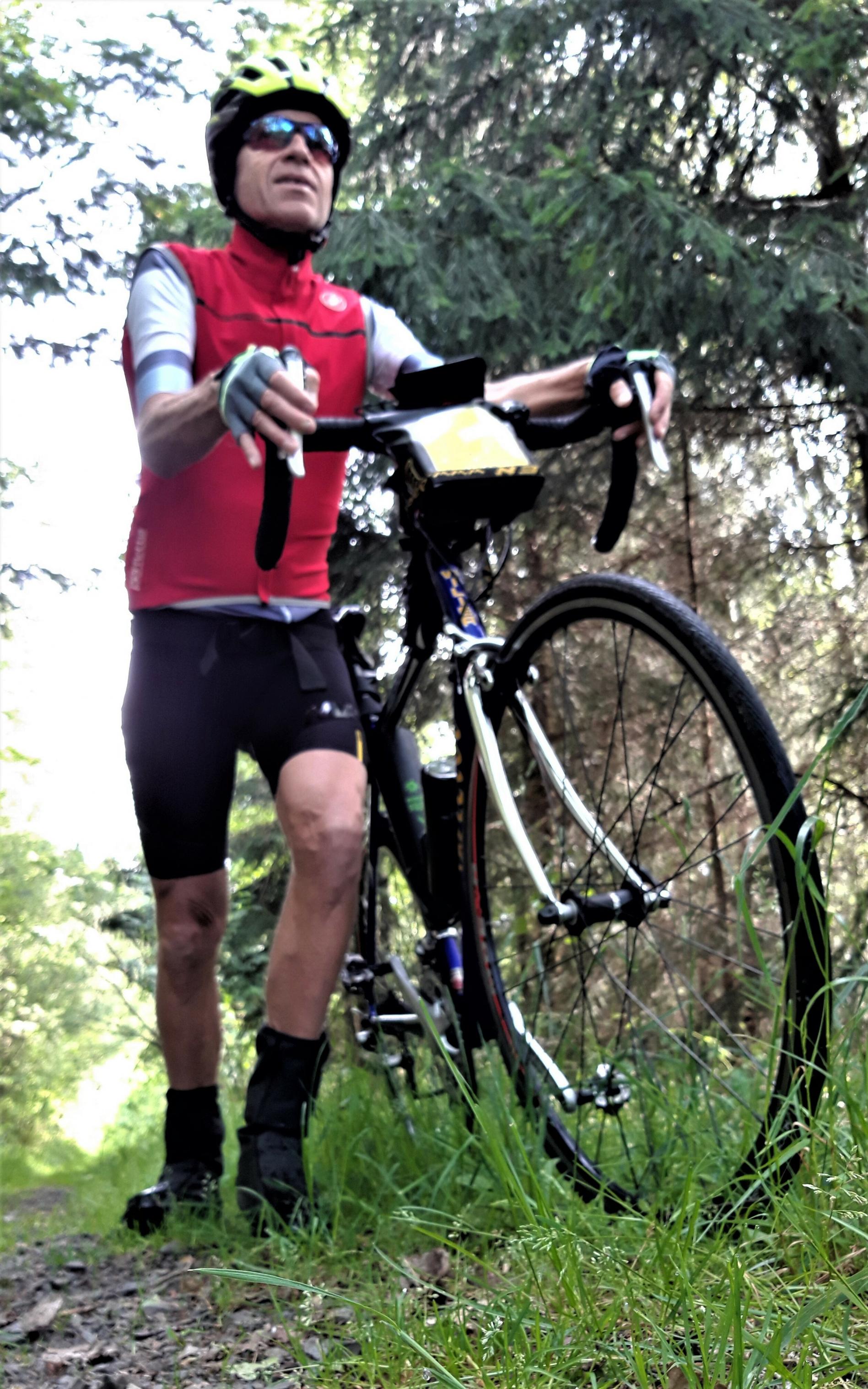Martin C. Roos schiebt sein Rennrad durch dichten Wald.