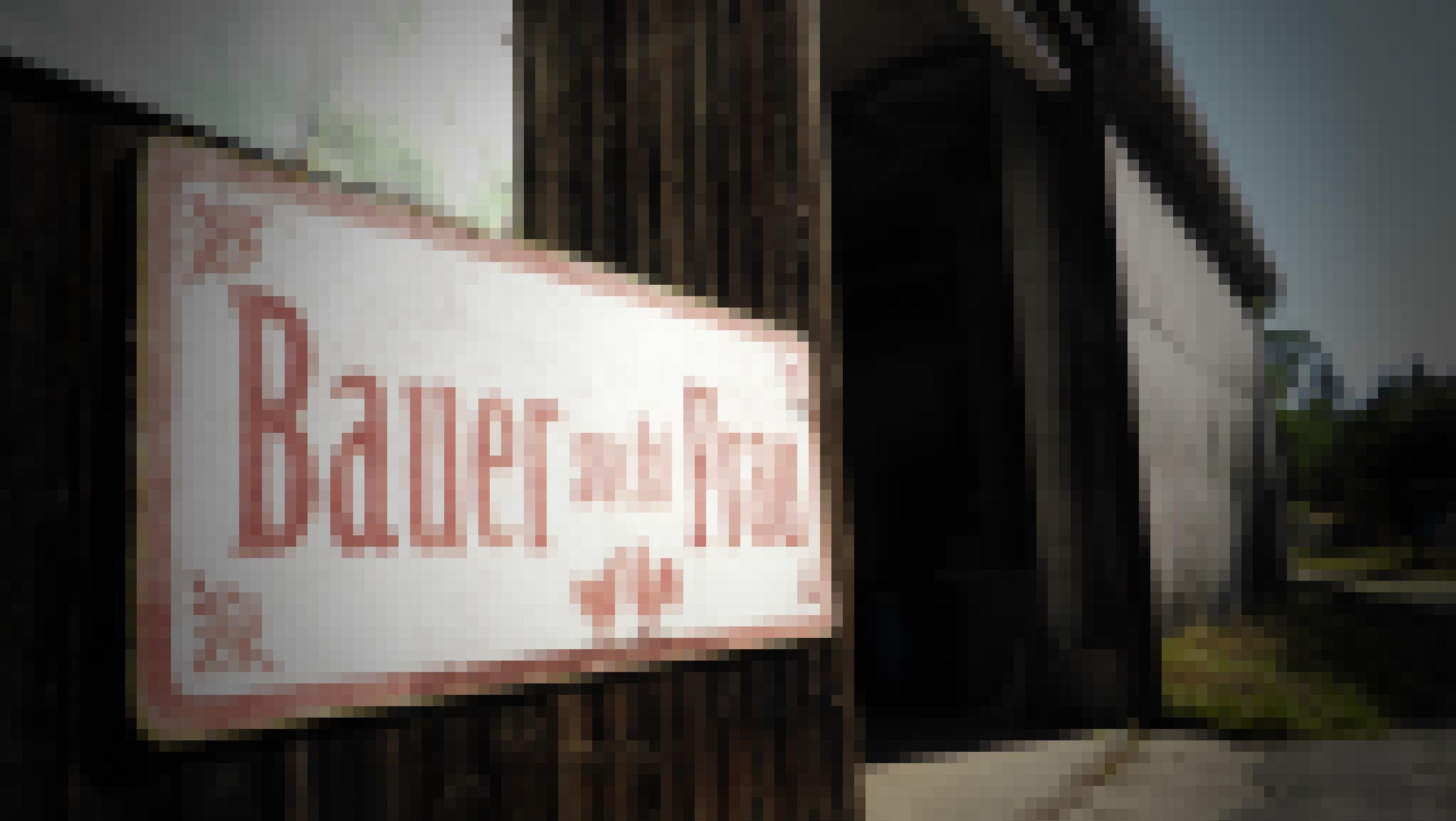 Rechts neben einer riesigen Scheuneneinfahrt prangt an der Holzwand das Schild „Bauer sucht Frau“ – rot auf weißem Grund.