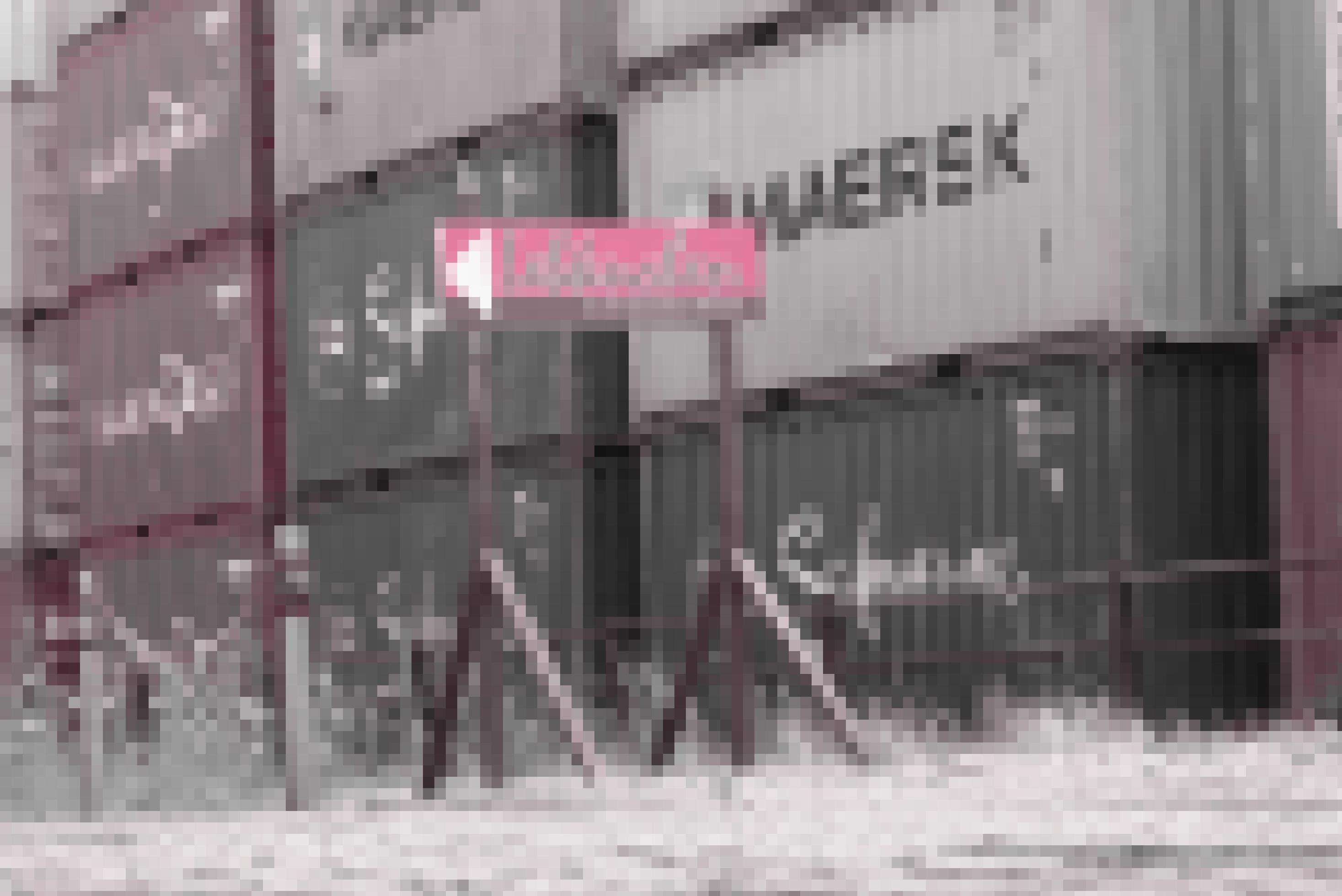 Hinweisschild einer Bremer Lebkuchen-Manufaktur vor dem Hintergrund gestapelter Schiffscontainer.