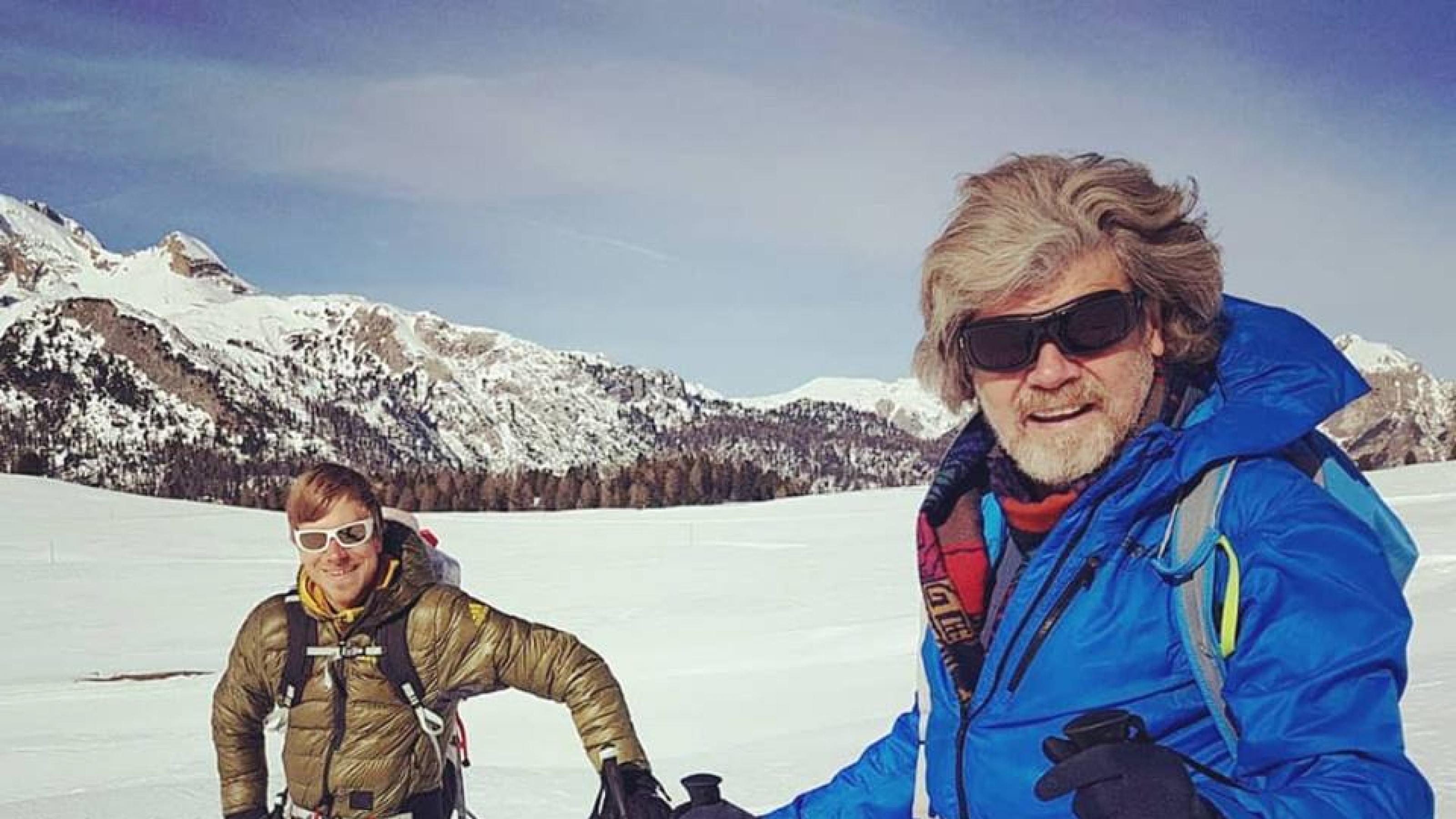 Vater und Sohn auf einem verschneiten Berghang in Skitourenausrüstung.