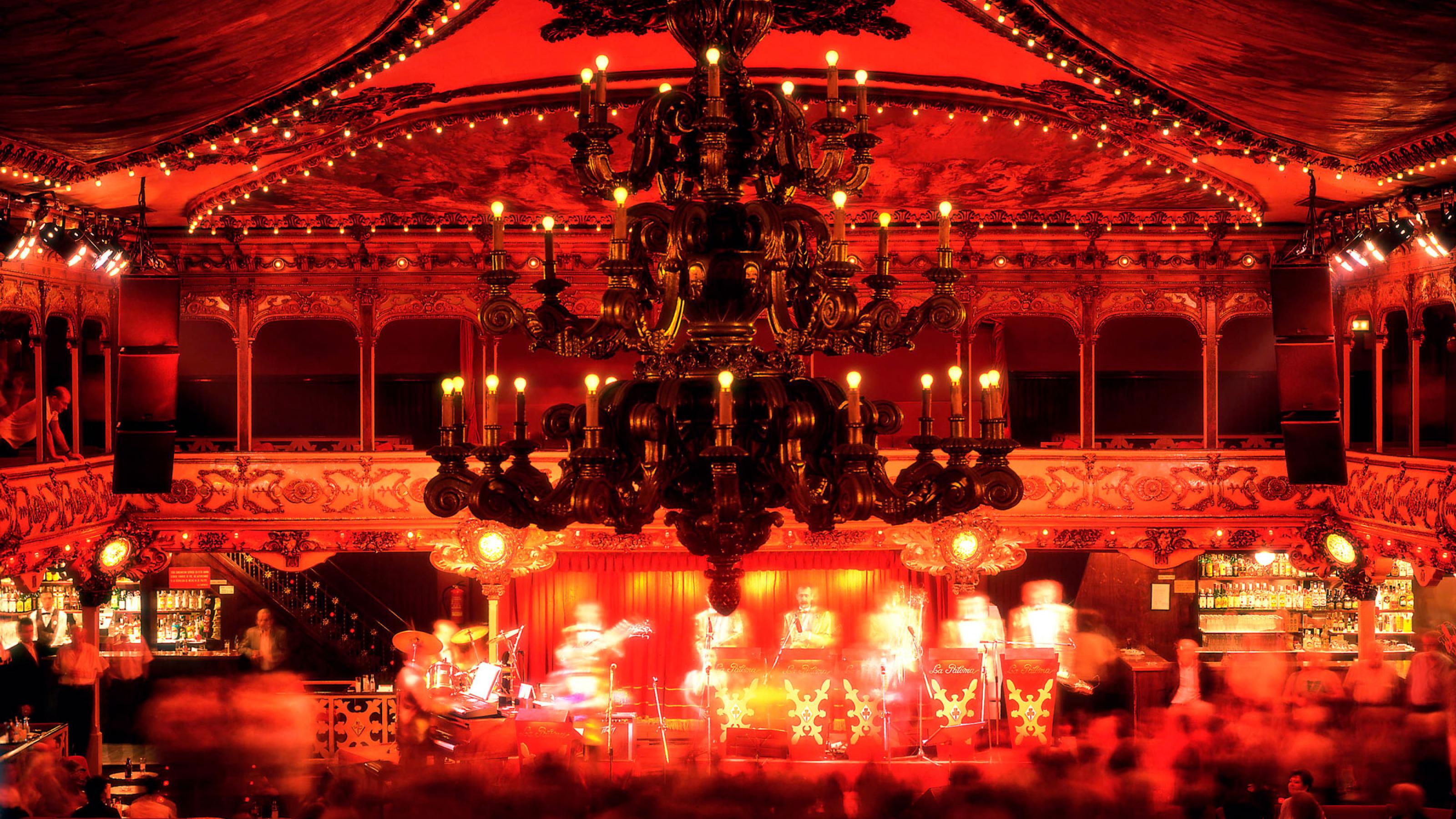 Komplett in Rot gehaltener Raumeindruck eines nächtlichen Tanzsaals voller Gäste.