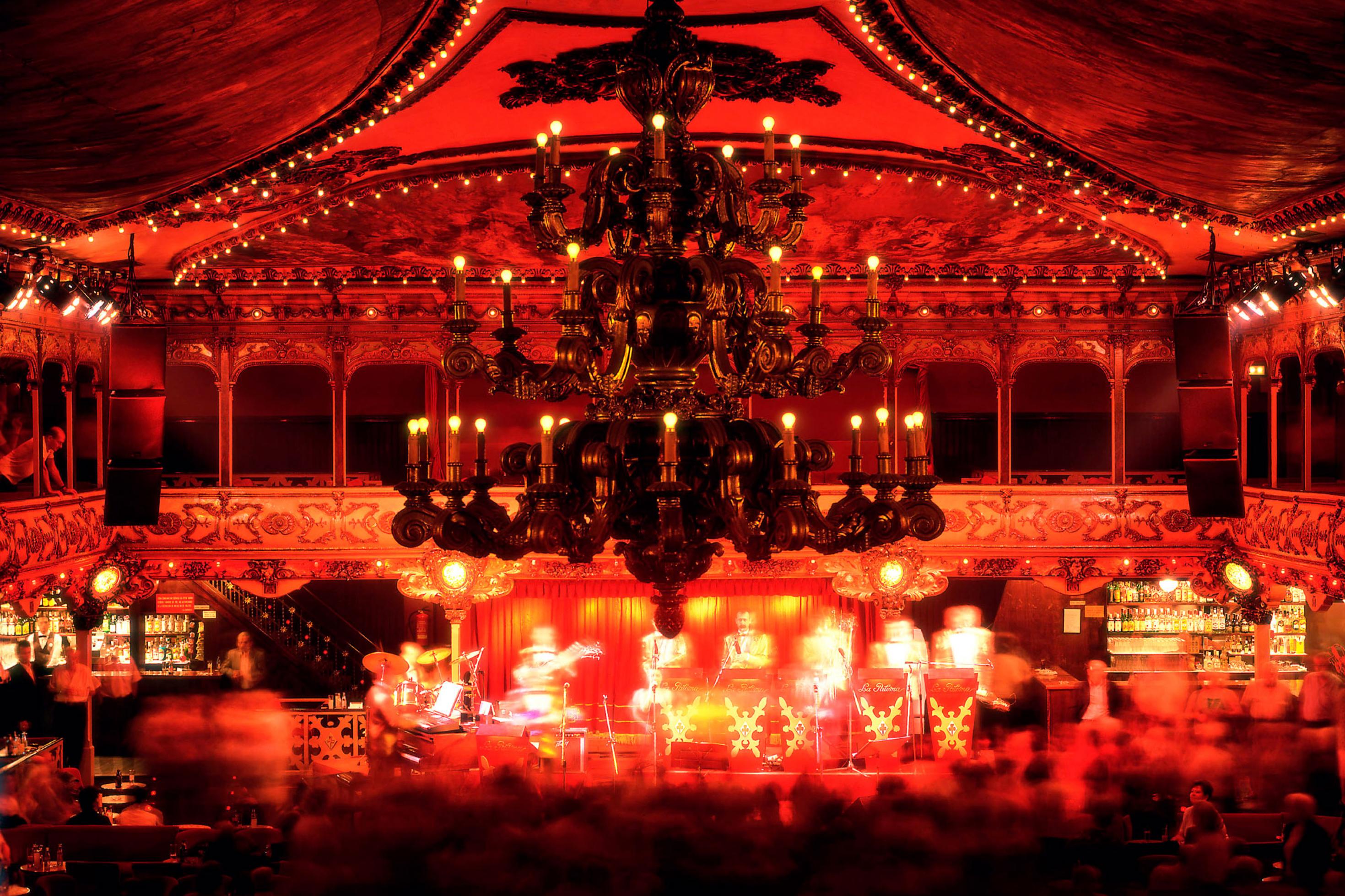 Komplett in Rot gehaltener Raumeindruck eines nächtlichen Tanzsaals voller Gäste.