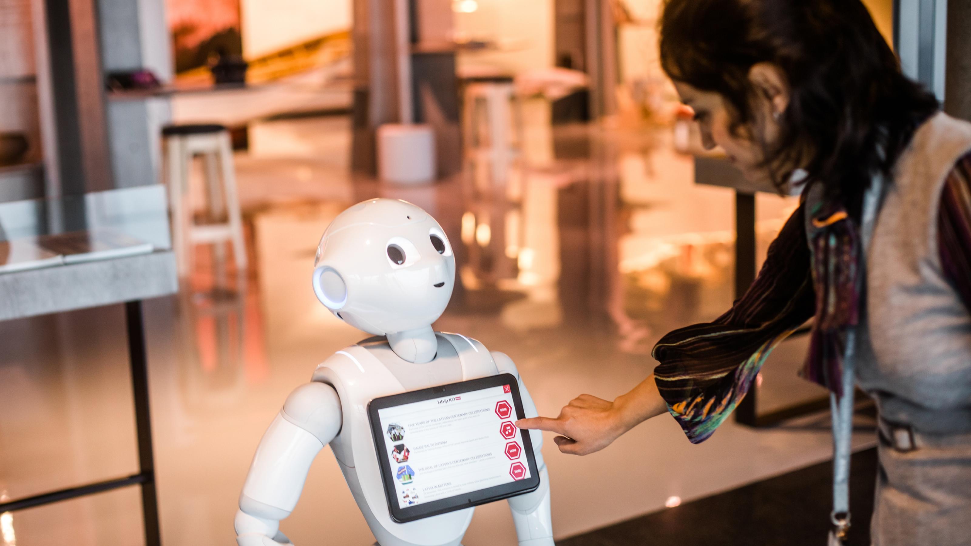 Ein Passagier erkundigt sich bei Roboter Pepper am Flughafen von Riga. Dank KI können Maschinen die Rolle eines sozialen Gegenübers übernehmen.