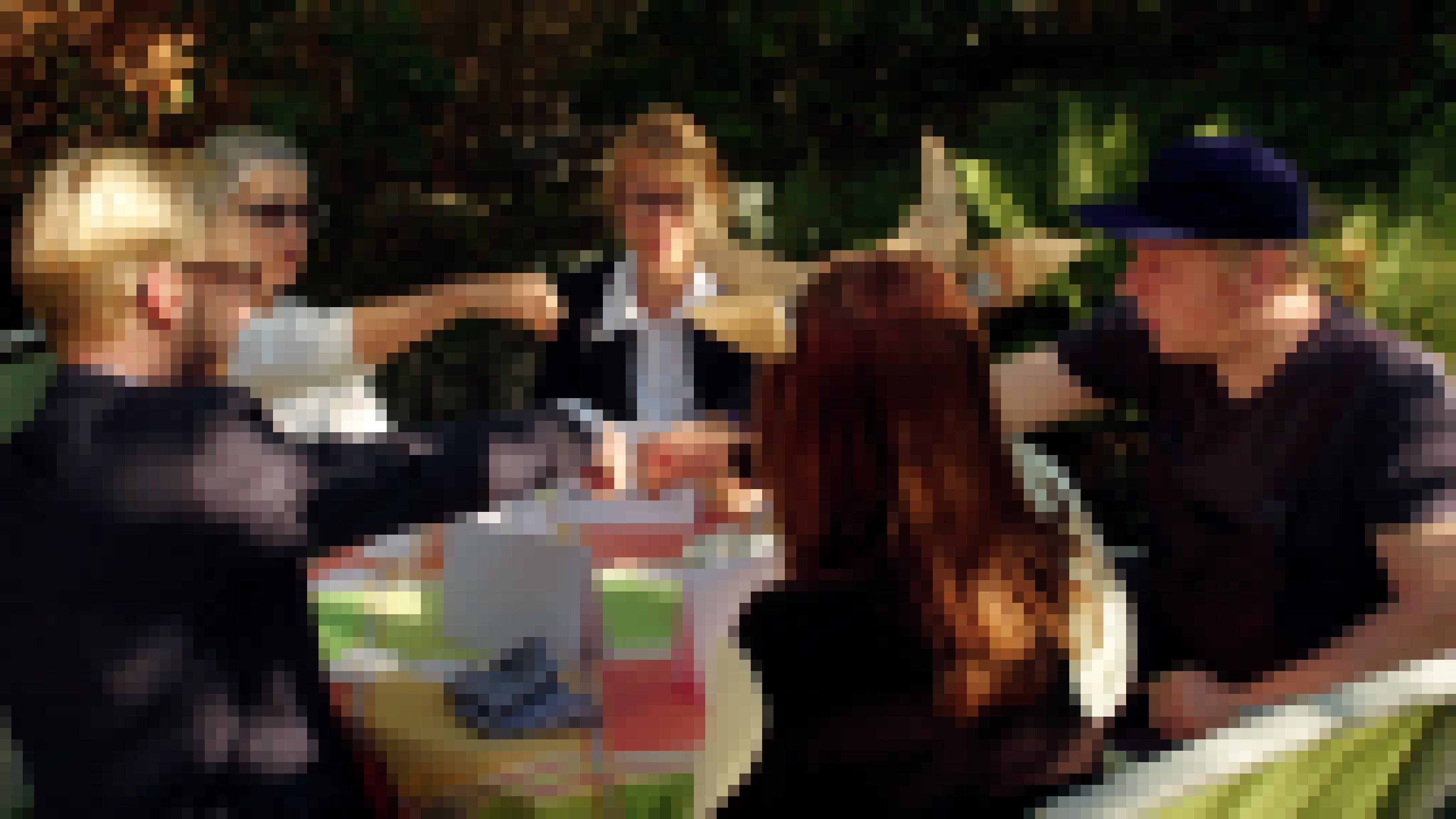 Fünf Spieler am Gartentisch, die ihre Arme zur Tischmitte ausstrecken.