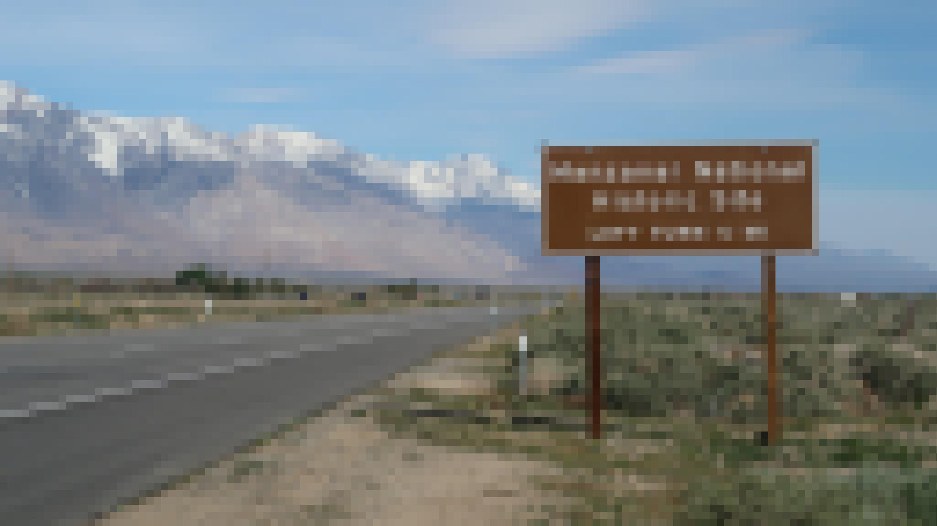 Ein Schild an einem Highway vor schneebedeckten Bergen.