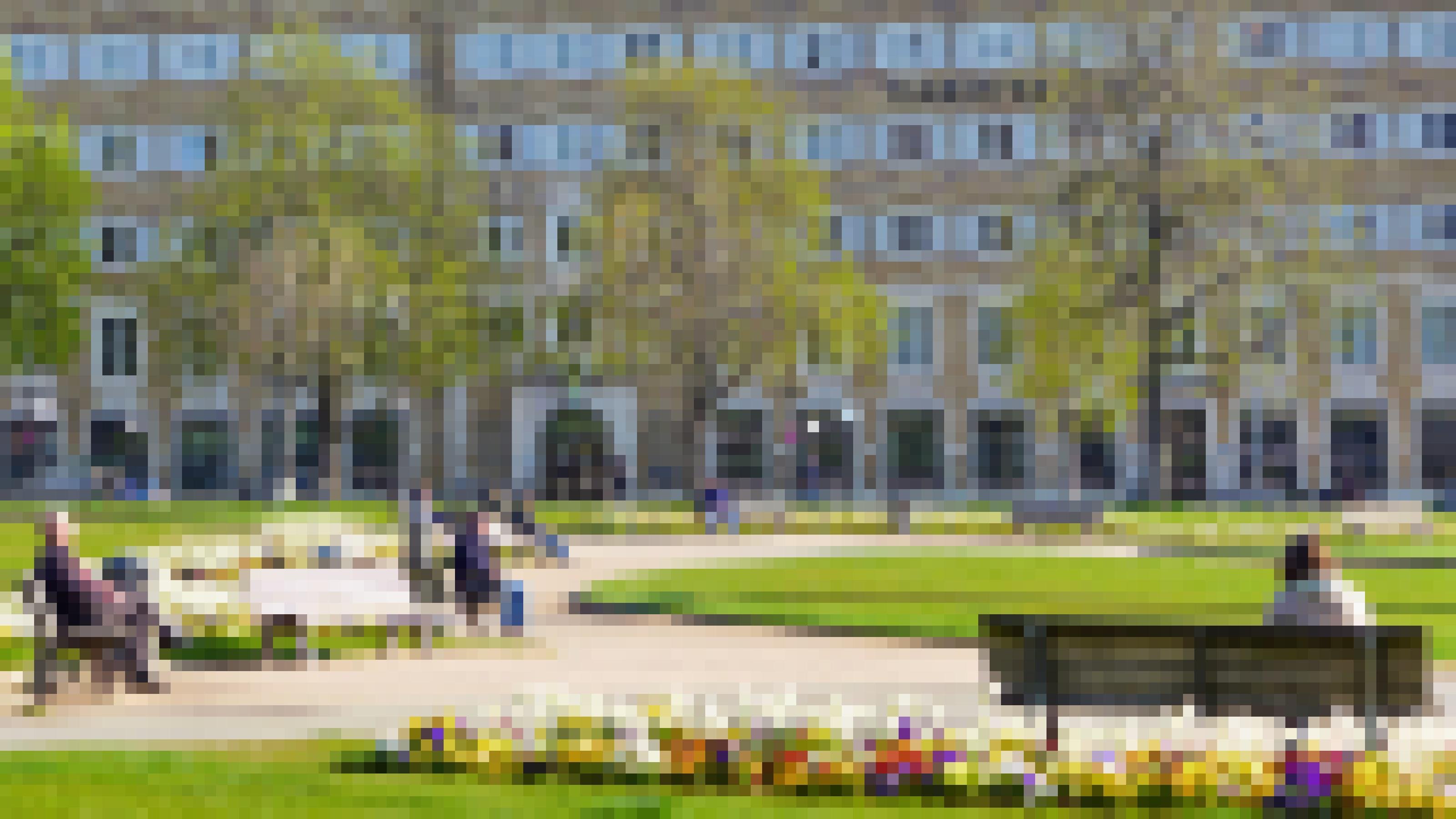 Auf dem Schlossplatz in Stuttgart sitzen Menschen in der Sonne. Sie halten Abstand zueinander.