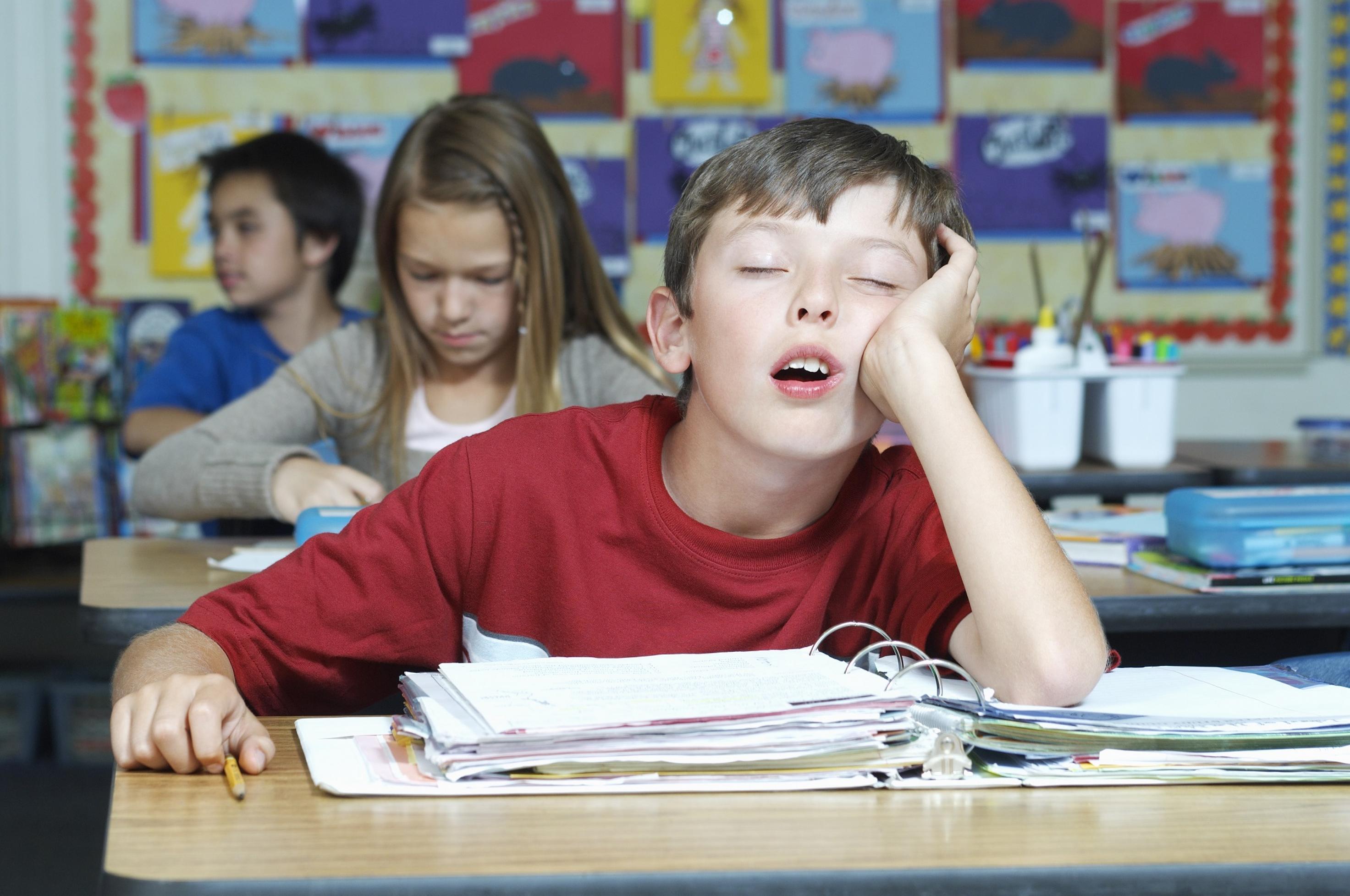 Drei Schüler in einem Klassenzimmer, einer davon schlafend