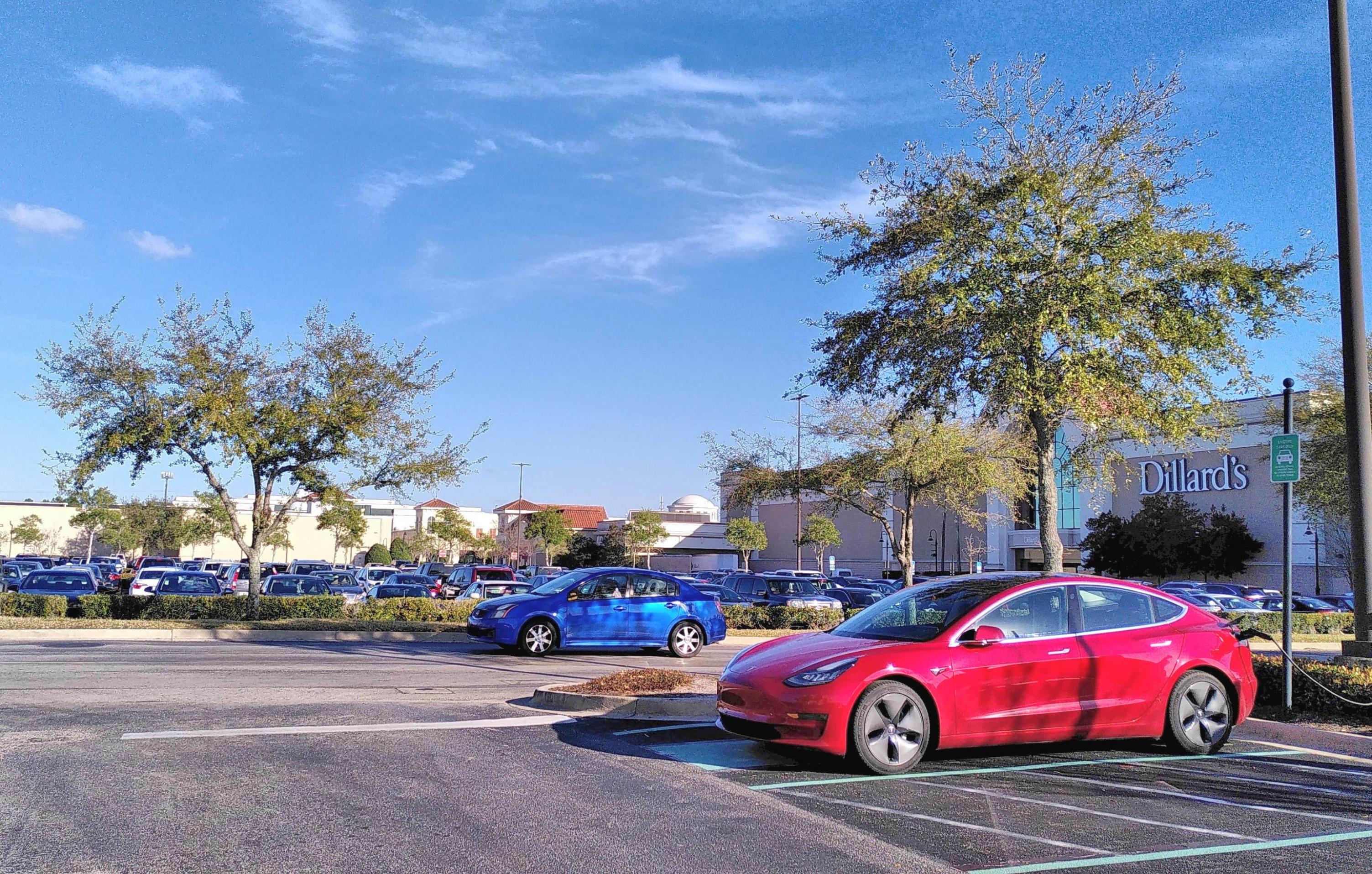 Ein roter Tesla steht auf einem Parkplatz.
