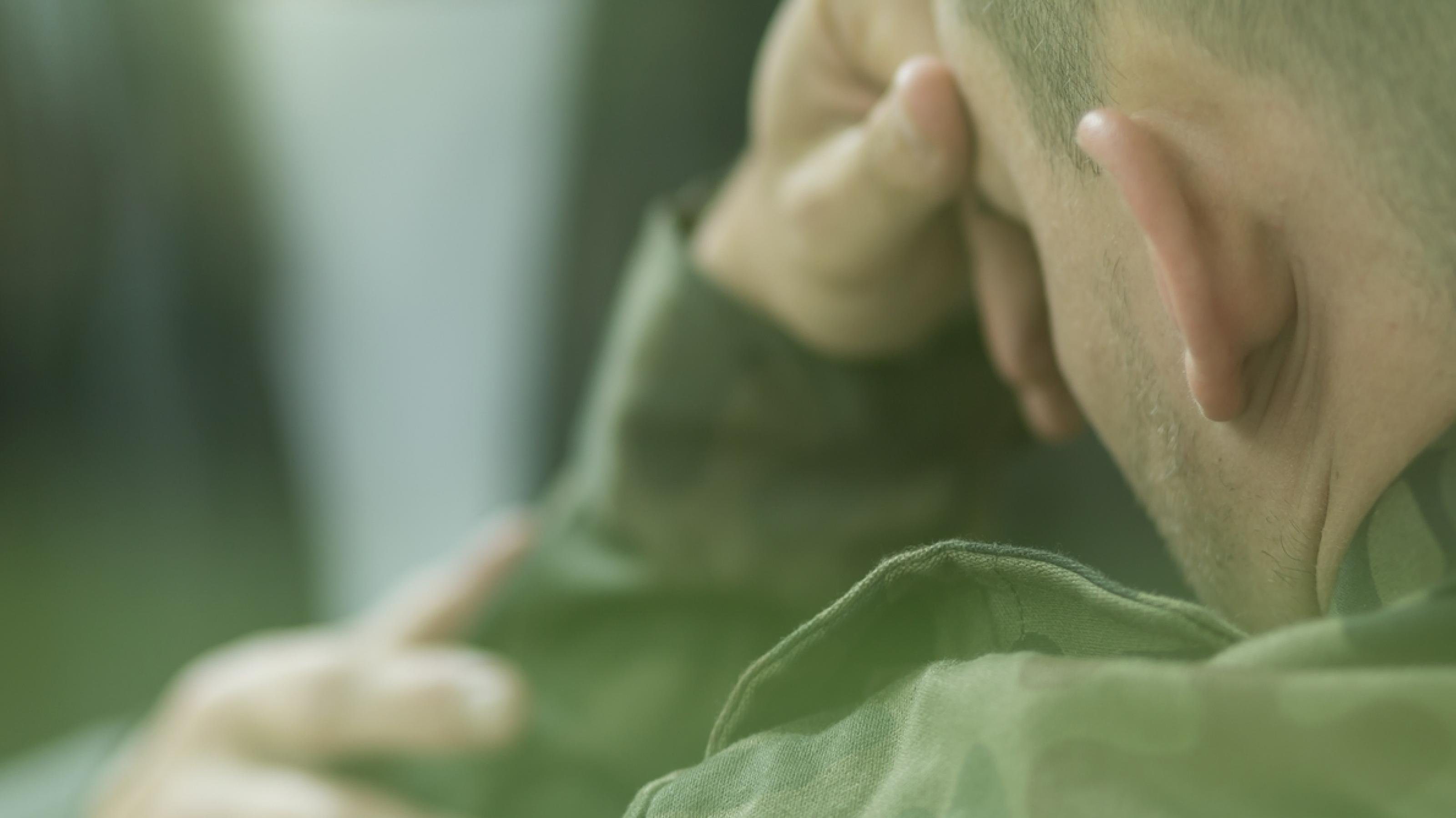 Ein Soldat sitzt abgewandt von der Kamera und verbirgt sein Gesicht hinter den Händen.