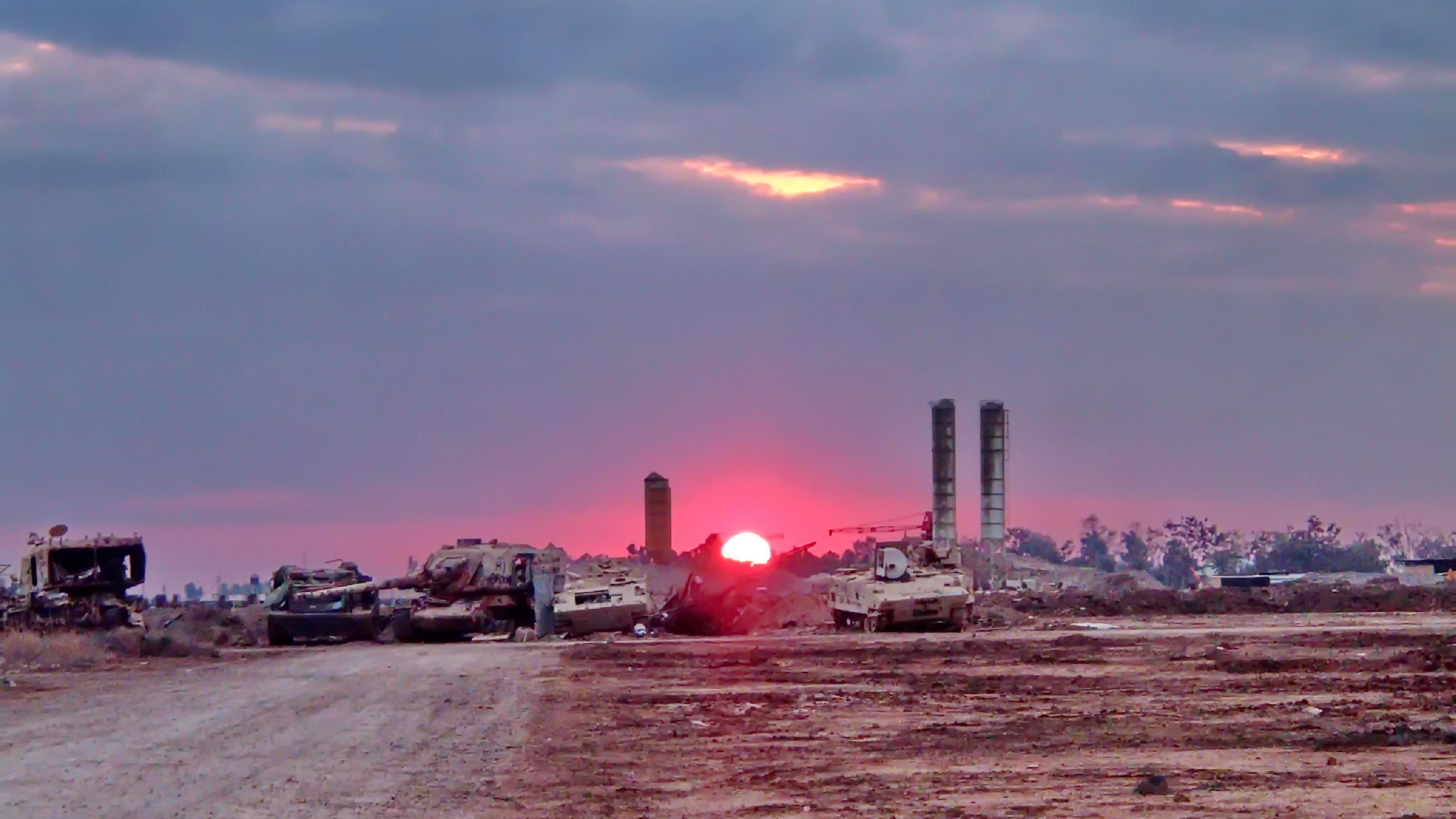 Ein Sonnenaufgang vor zerstörtem Militärgerät im Irak.
