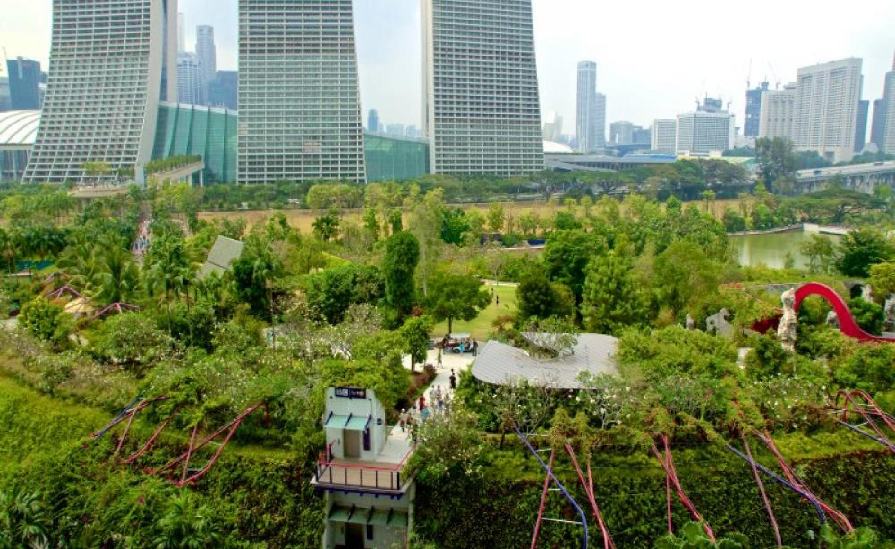 Aufnahme einer großen Gartenlandschaft aus der Luft. Im Hintergrund lässt sich eine Großstadt mit Hochhäusern erkennen.