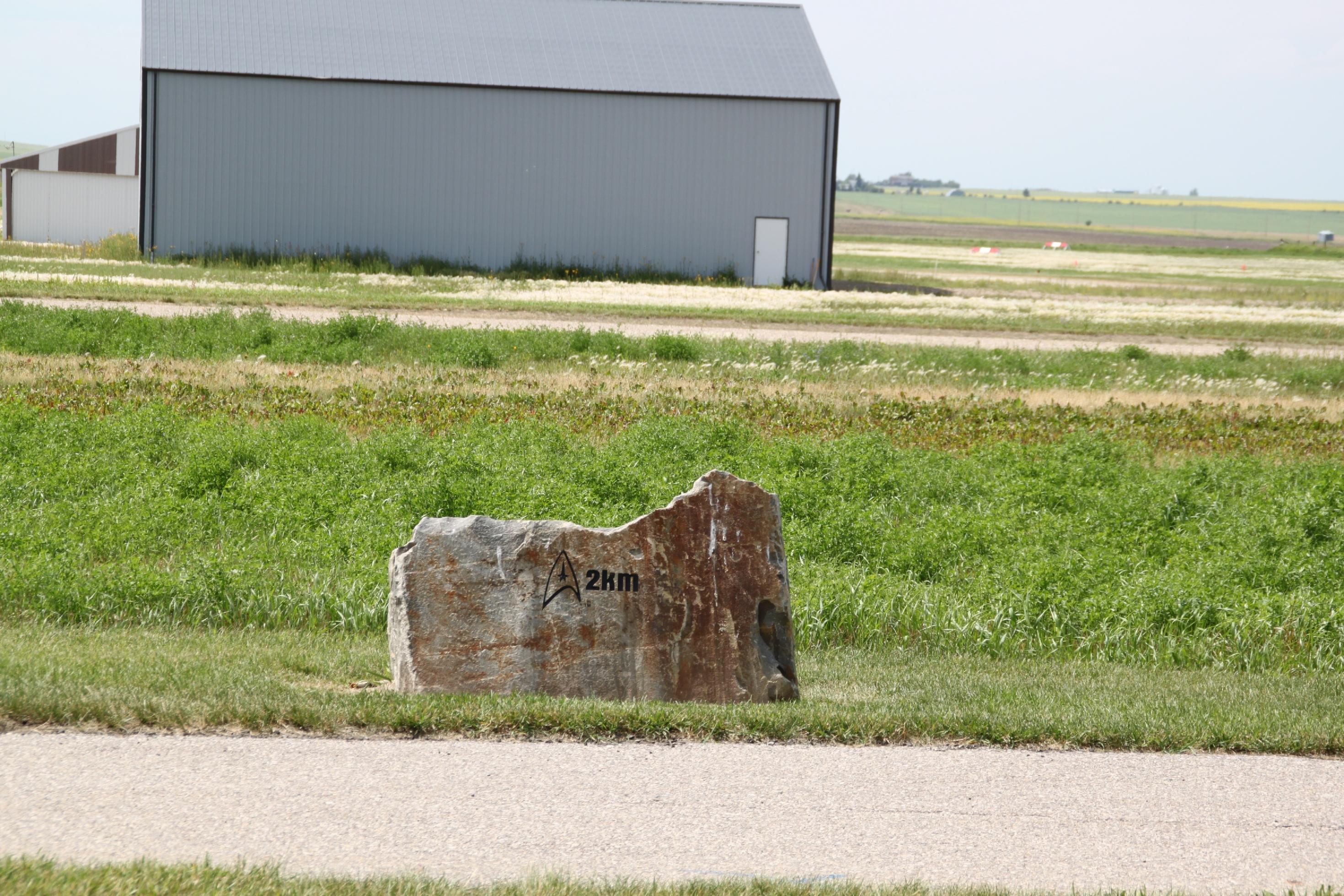 Auf einem Stein ist ein Star-Trek-Delta eingraviert. Dazu der Hinweis „2 km“.