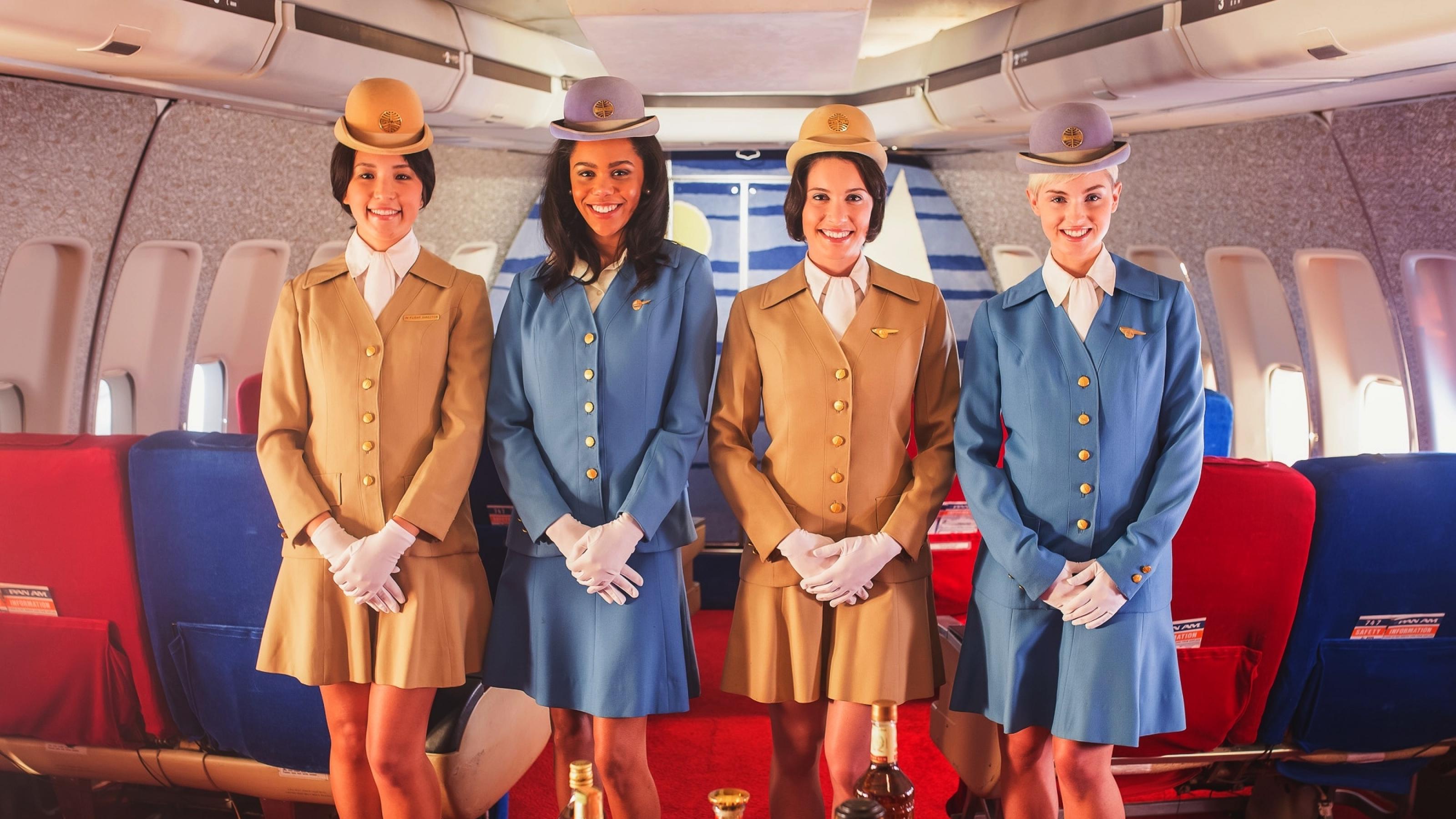 Vier Stewardessen stehen lächelnd in einer Flugzeugkabine
