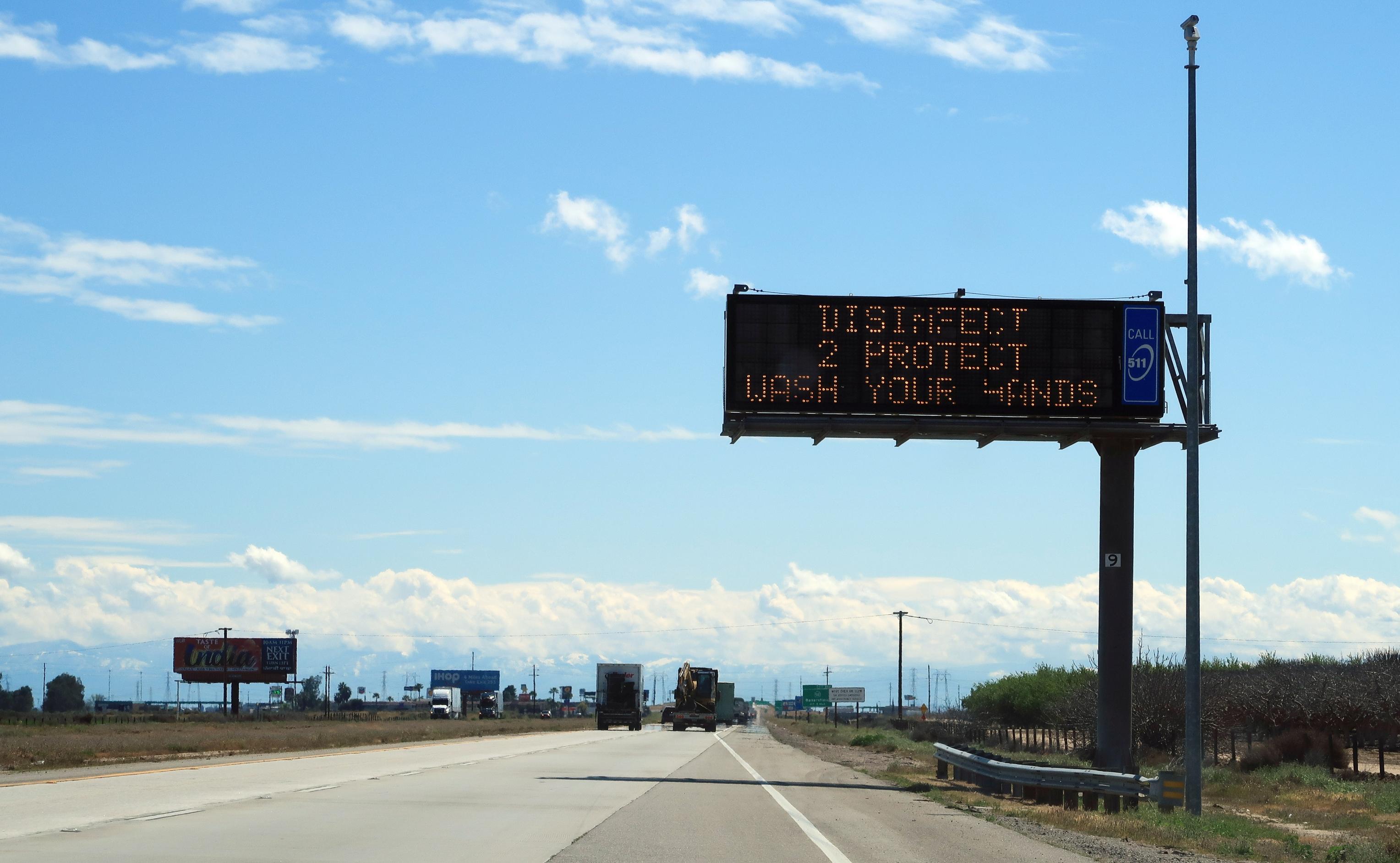 Hinweisschild über einer Autobahn mit der Aufschrift „Wash your hands“.